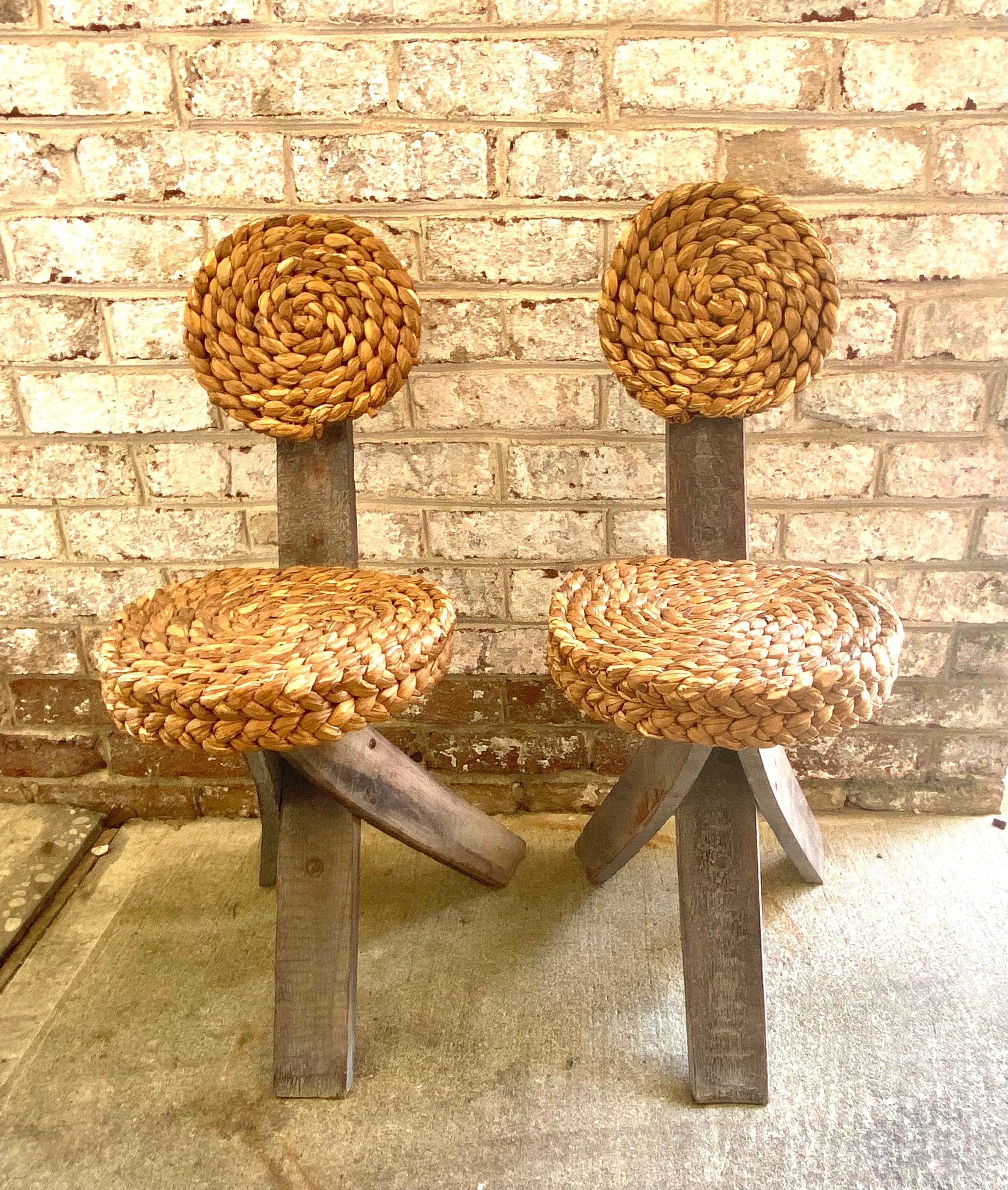 A unique pair of Audoux Minet tripod base chairs with abaca seats and backs.