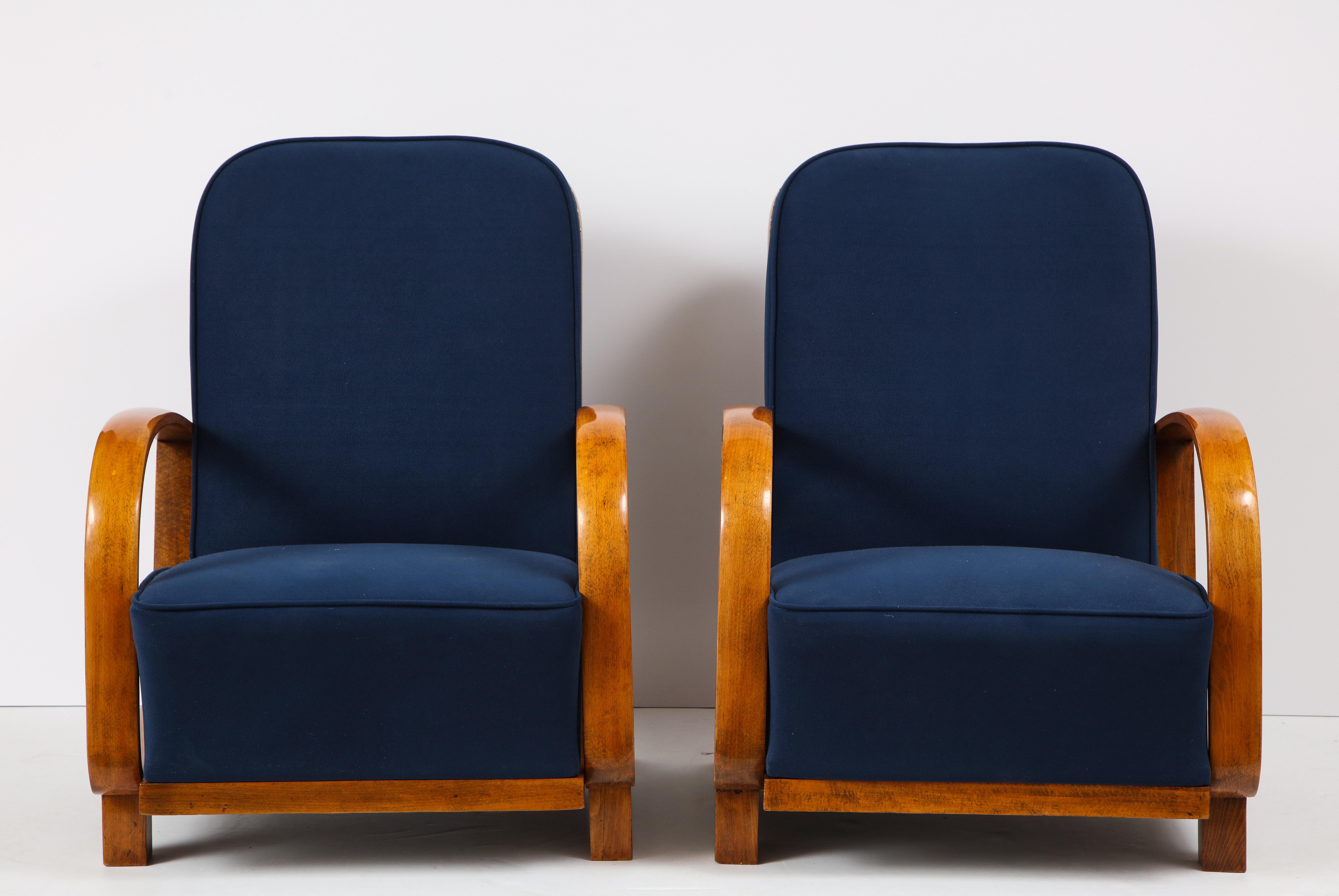 Pair of large and very comfortable Austrian Art Deco fruit-wood armchairs; the sloped wood arms beautifully shaped and extend to form the molded side, with curved wood back rest and shaped structural base support. Newly upholstered in a rich blue