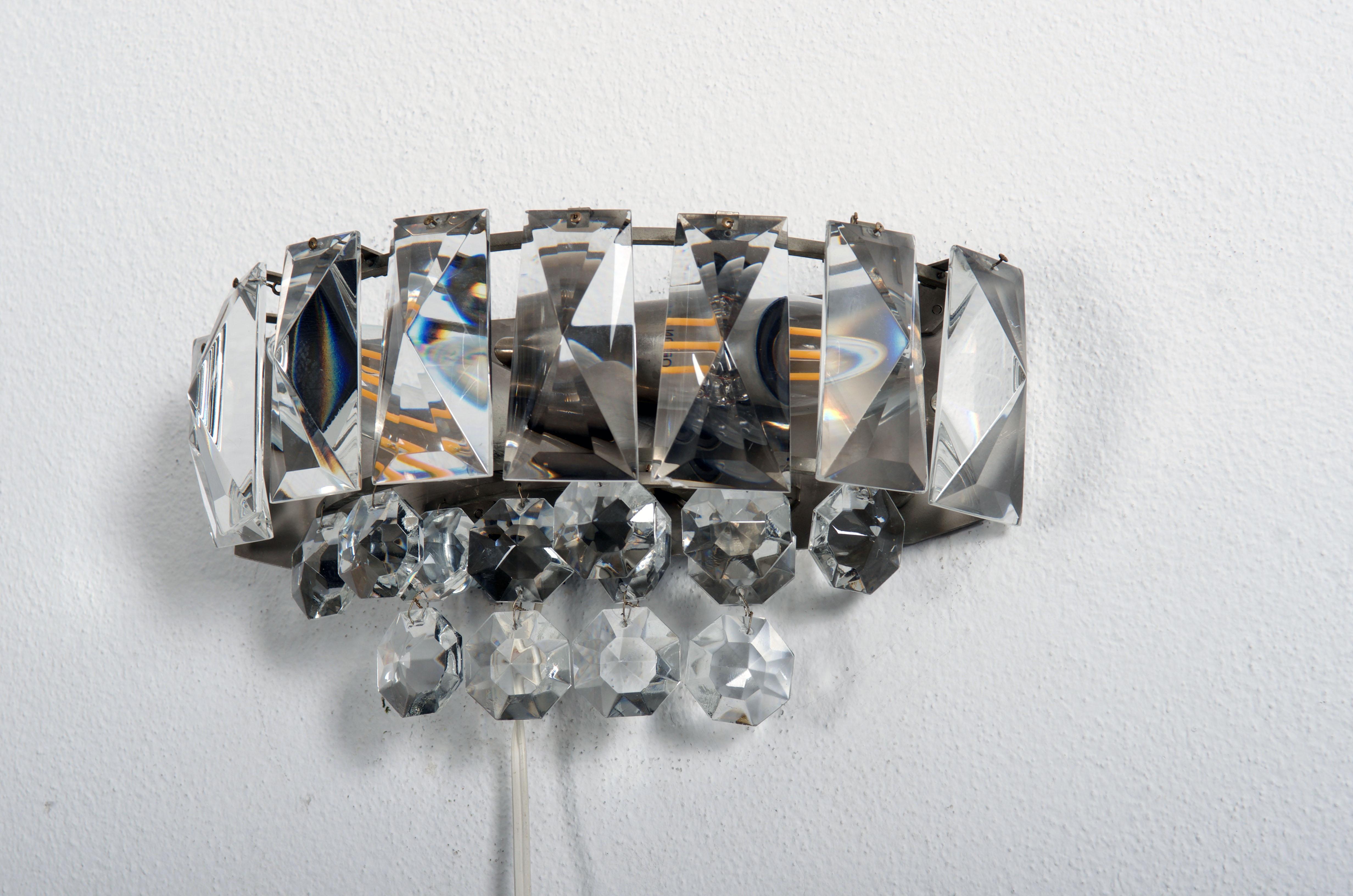 Brass frame nickel-plated fitted with two E14 sockets up to 60Watts.
Covered with faceted crystal prisms.
Manufactures in Vienna in the late the 1960s by Bakalowits & Söhne. 
Two pieces available.
Price per piece.