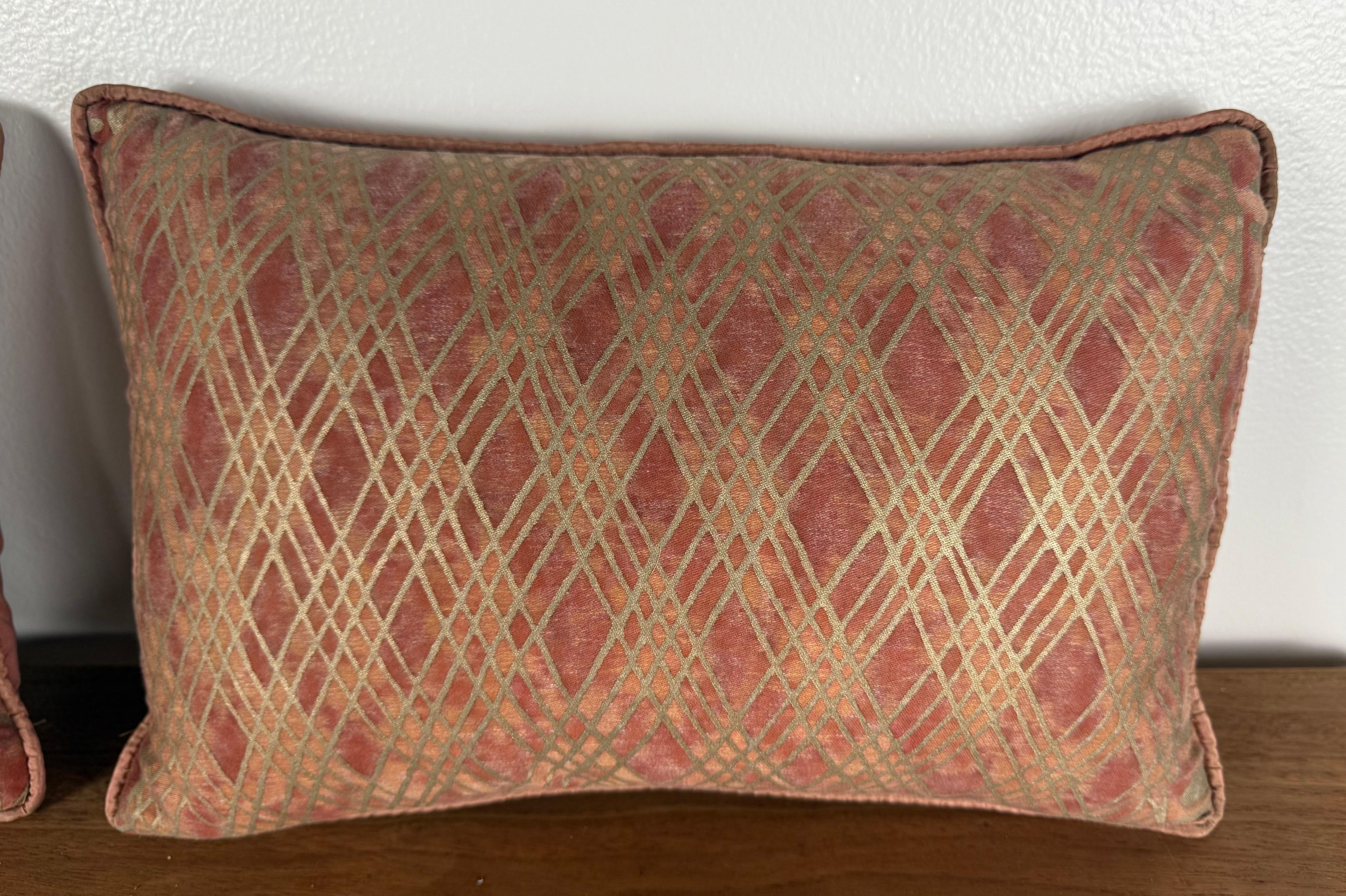 Una raffinata coppia di autentici cuscini Fortuny realizzati con un classico motivo geometrico a reticolo Fortuny, caratterizzato da linee intrecciate disposte in un ritmico e architettonico disegno incrociato. Il tessuto presenta uno splendido