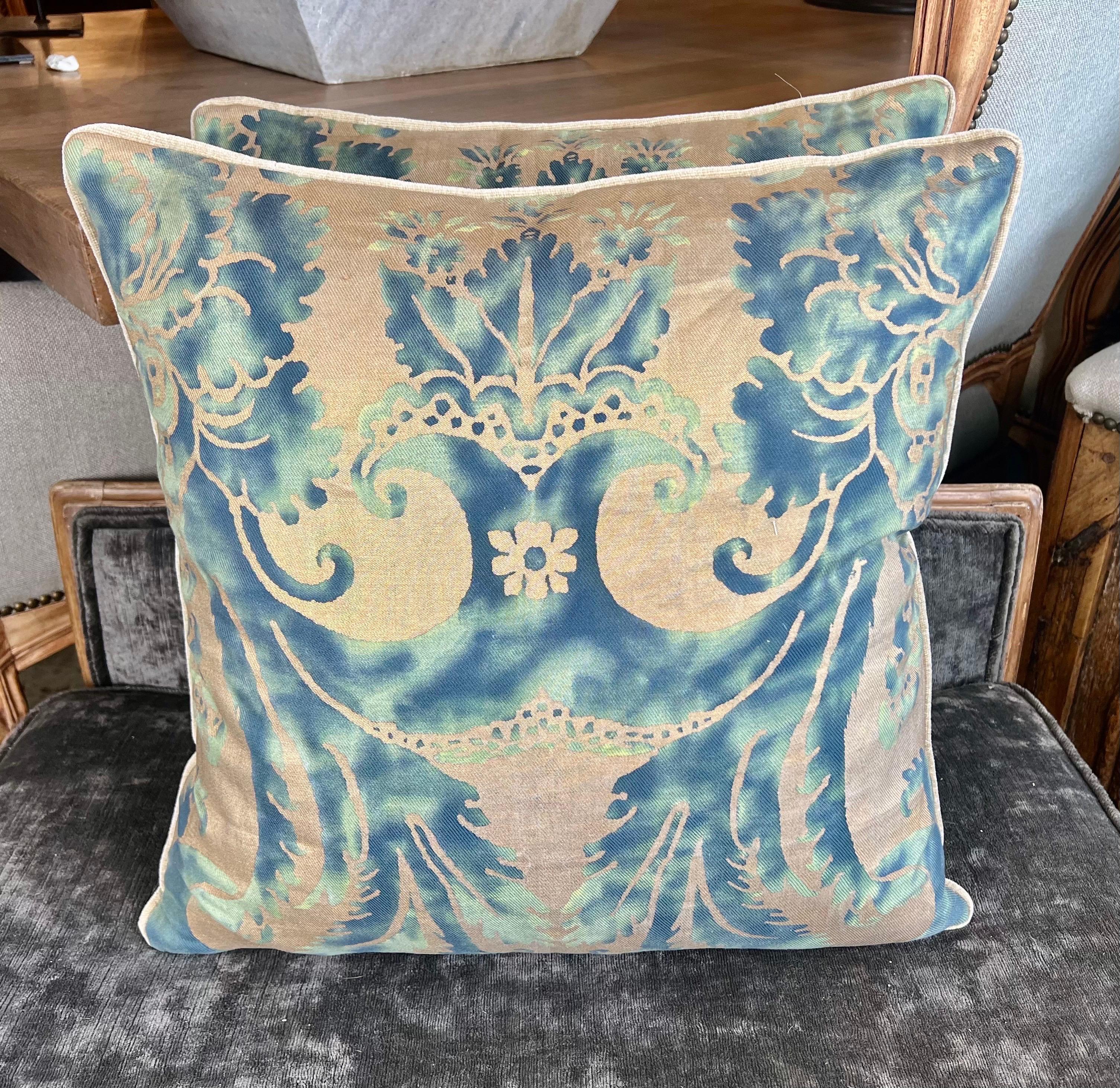 Coppia di cuscini in tessuto Fortuny, noto per i suoi lussuosi disegni stampati a mano dal caratteristico stile veneziano.  Si tratta di uno degli stili classici di Fortuny che spesso presenta motivi di ispirazione barocca o rinascimentale, come i