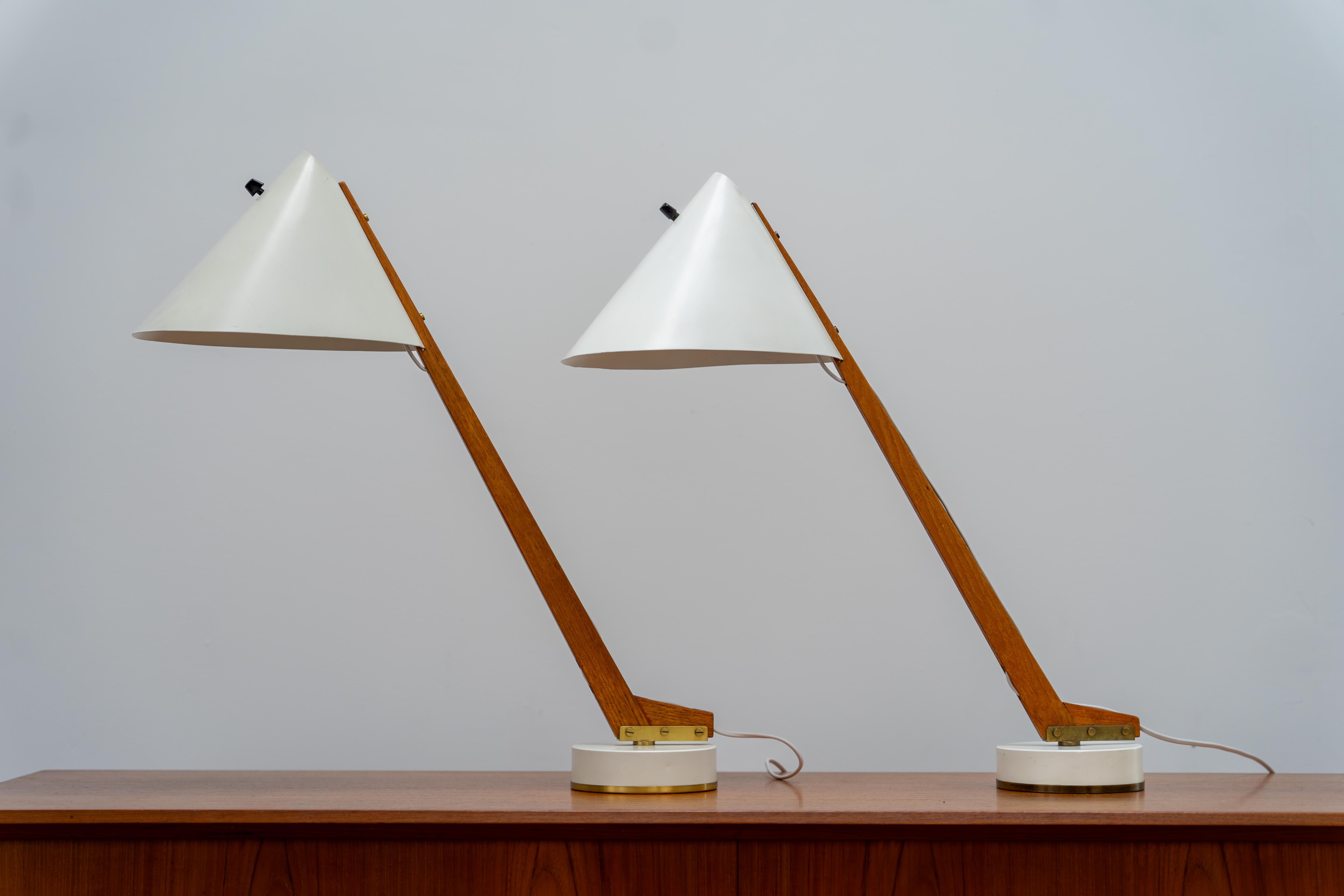 Elegante par de lámparas de sobremesa del famoso diseñador sueco Hans-Agne Jakobsson para Markaryd, diseñadas en 1955. Cada lámpara tiene un brazo de teca maciza, una pantalla y una base originales de metal lacado en blanco y detalles de latón. La