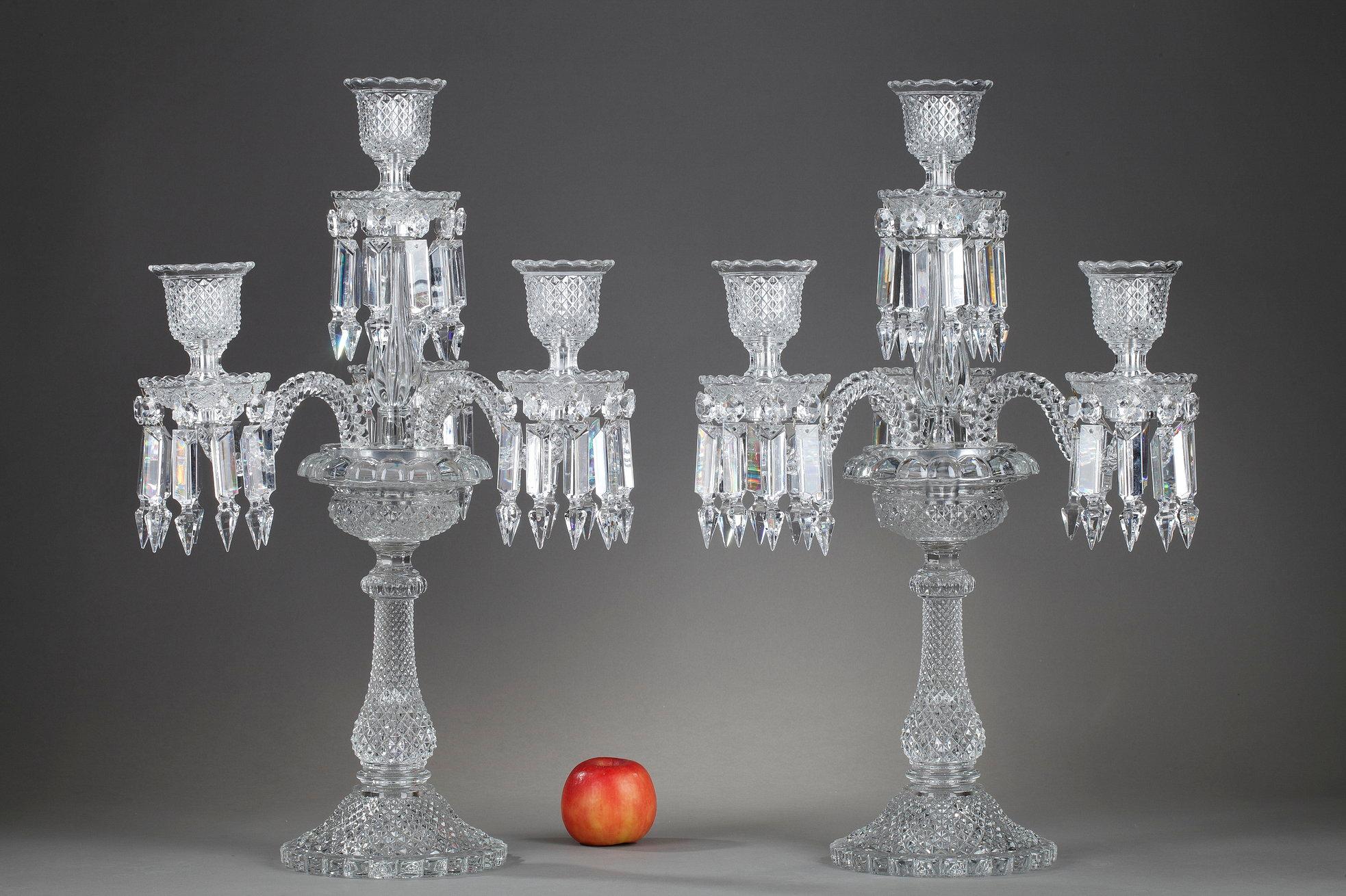 Pair of Baccarat candelabras in molded crystal with four lights. Those candlesticks are composed of three twisted arms of lights decorated with geometrical pendants and an upper post. The shaft is decorated with a guilloche pattern. The base is made