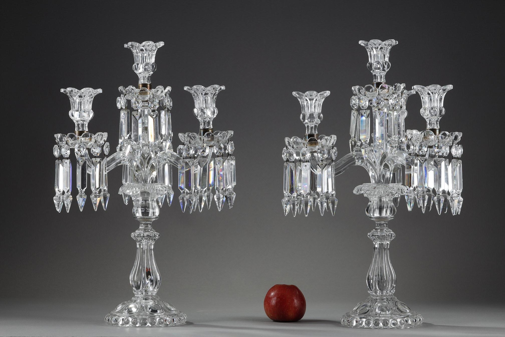 Pair of crystal girandoles with four lights on two levels from the Baccarat House. They are decorated with geometrical crystal pendants, the shafts are ringed and the feet have gadroon motifs. 

It is a production of the 20th century made by the