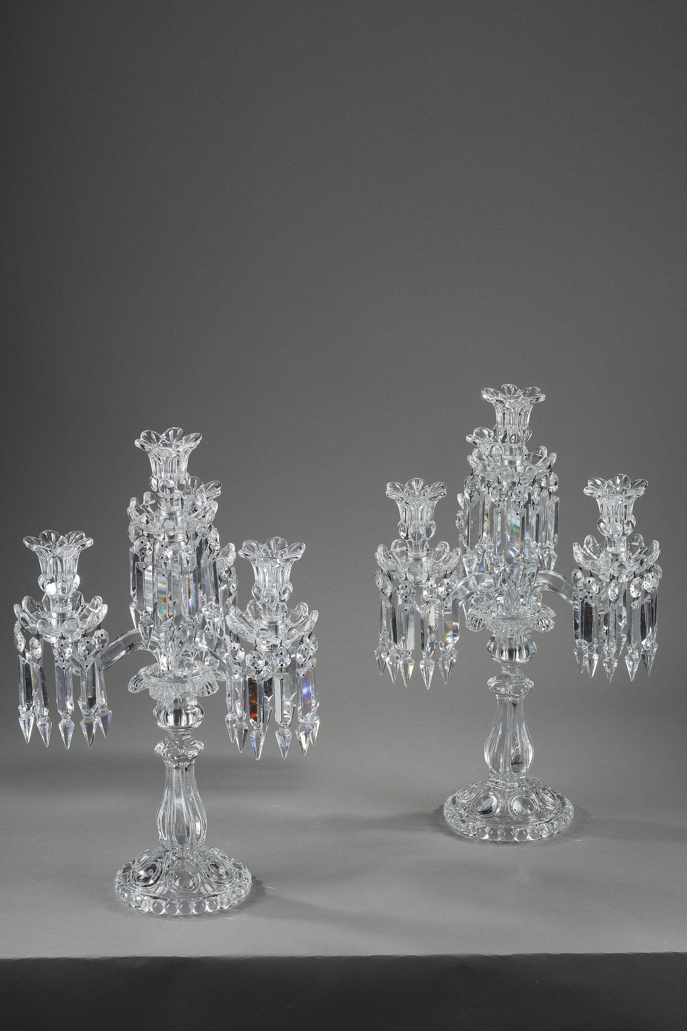 Pair of Baccarat four-light, two-tier crystal girandoles. They are decorated with geometric crystal pendants, the shafts are ringed and the feet feature gadroon motifs.

This is a 20th-century Baccarat production.

The Baccarat crystal works are