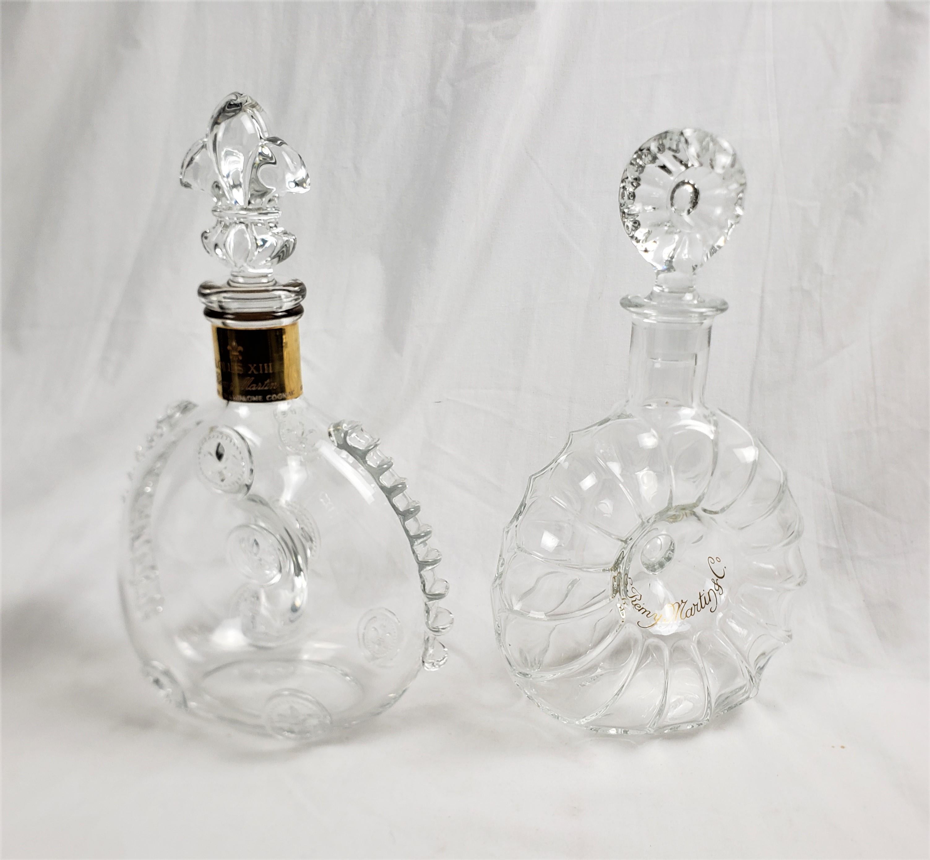 This pair of liquor decanters were made by the renowned Baccarat Compay of France in approximately 1965 in a Louis XIII style. The decanters are composed of crystal and once held Remy Martin French cognac. One is decorated with a fleur de lis