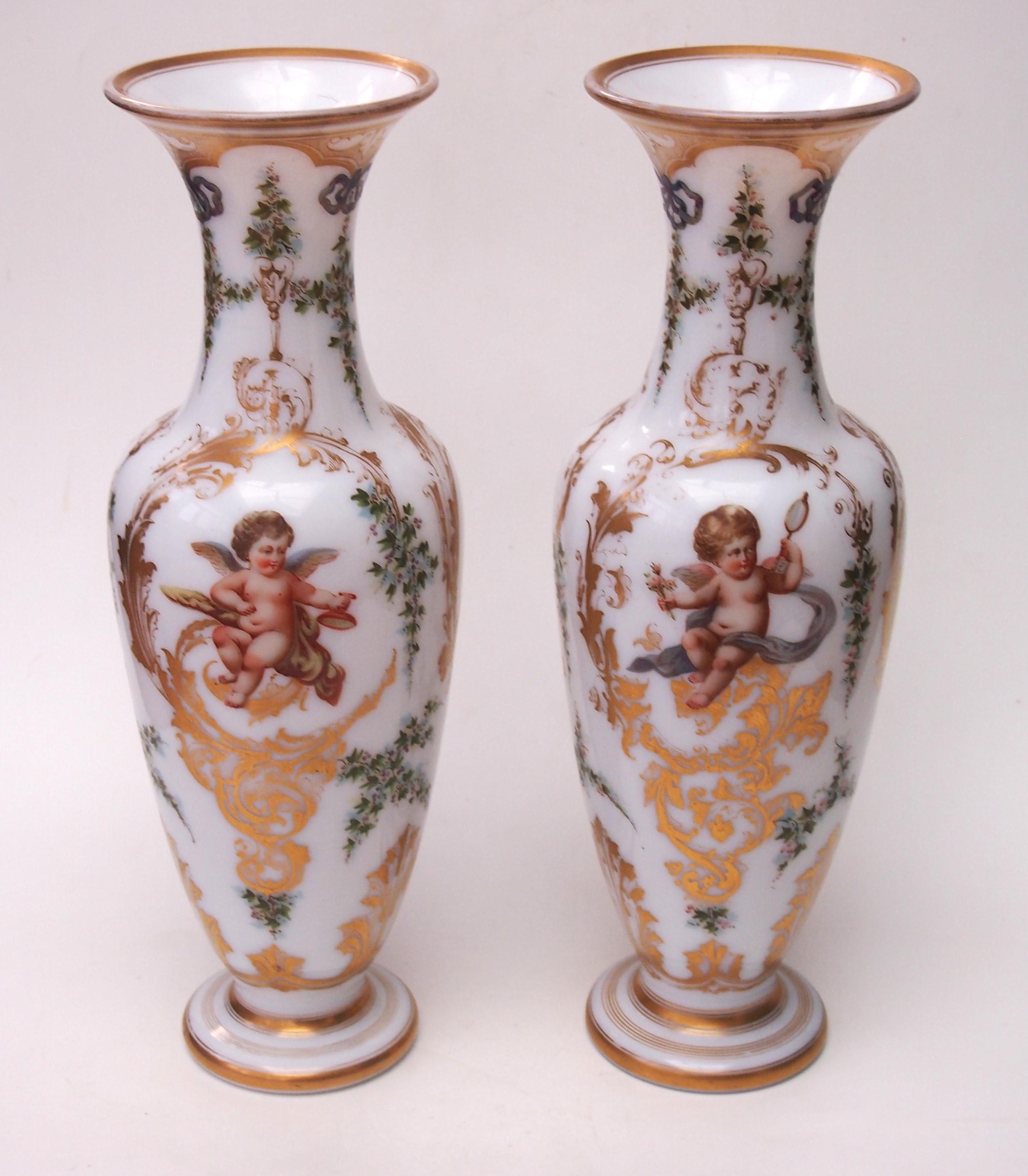 Magnifique paire de vases de forme balustre en forme de chérubins émaillés d'opaline de Baccarat. Chaque vase est décoré d'un fin émail polychrome représentant trois chérubins différents,  deux avec des arcs, un avec des tambours, un avec un oiseau,