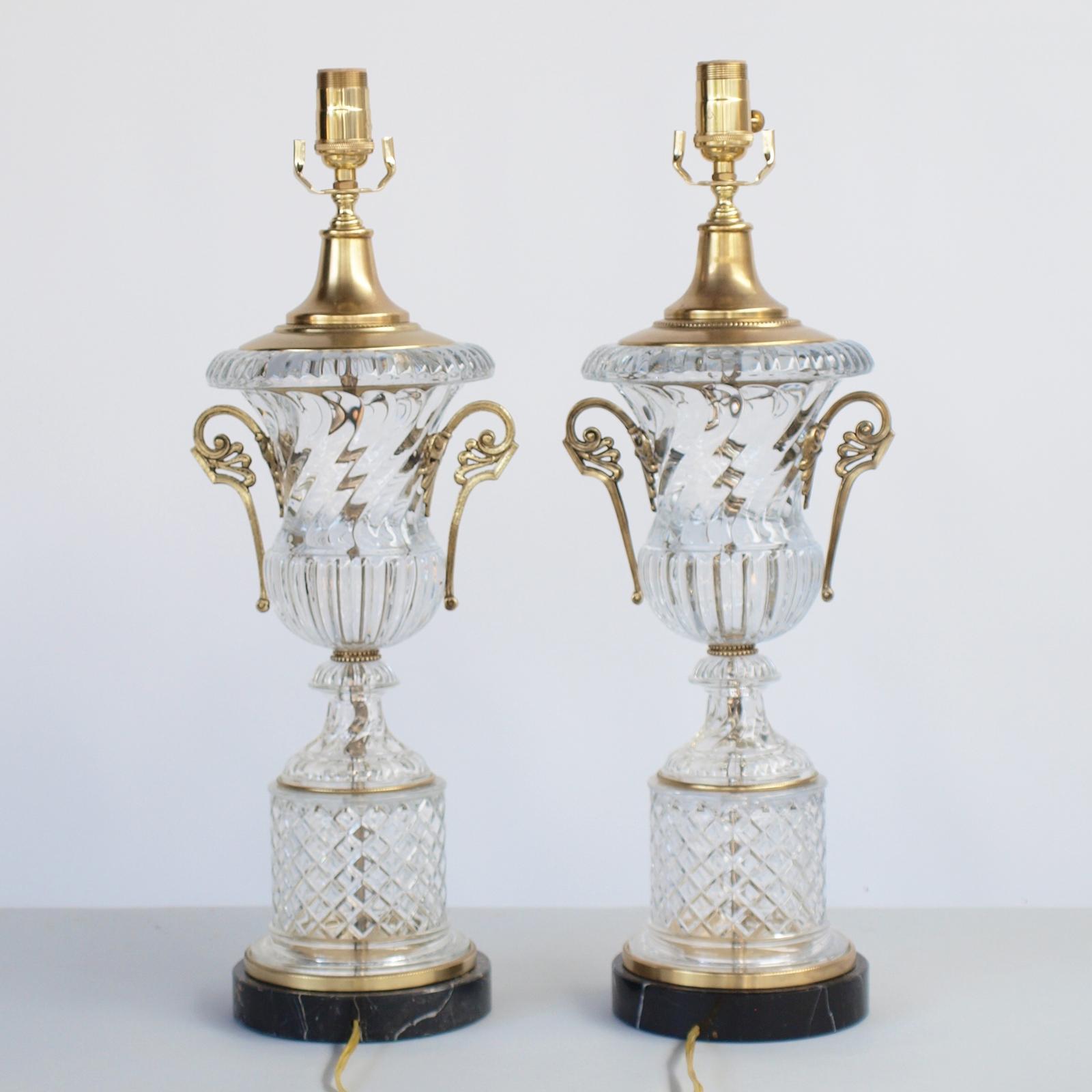 Fine pair of glass lamps, from the original Baccarat molds, by Paul Hanson; each a spiraling urn with gilt bronze scrolling handles, on round plinth cut in diamond pattern, on a base of black marble.  Shown with pleated silk shades (not
