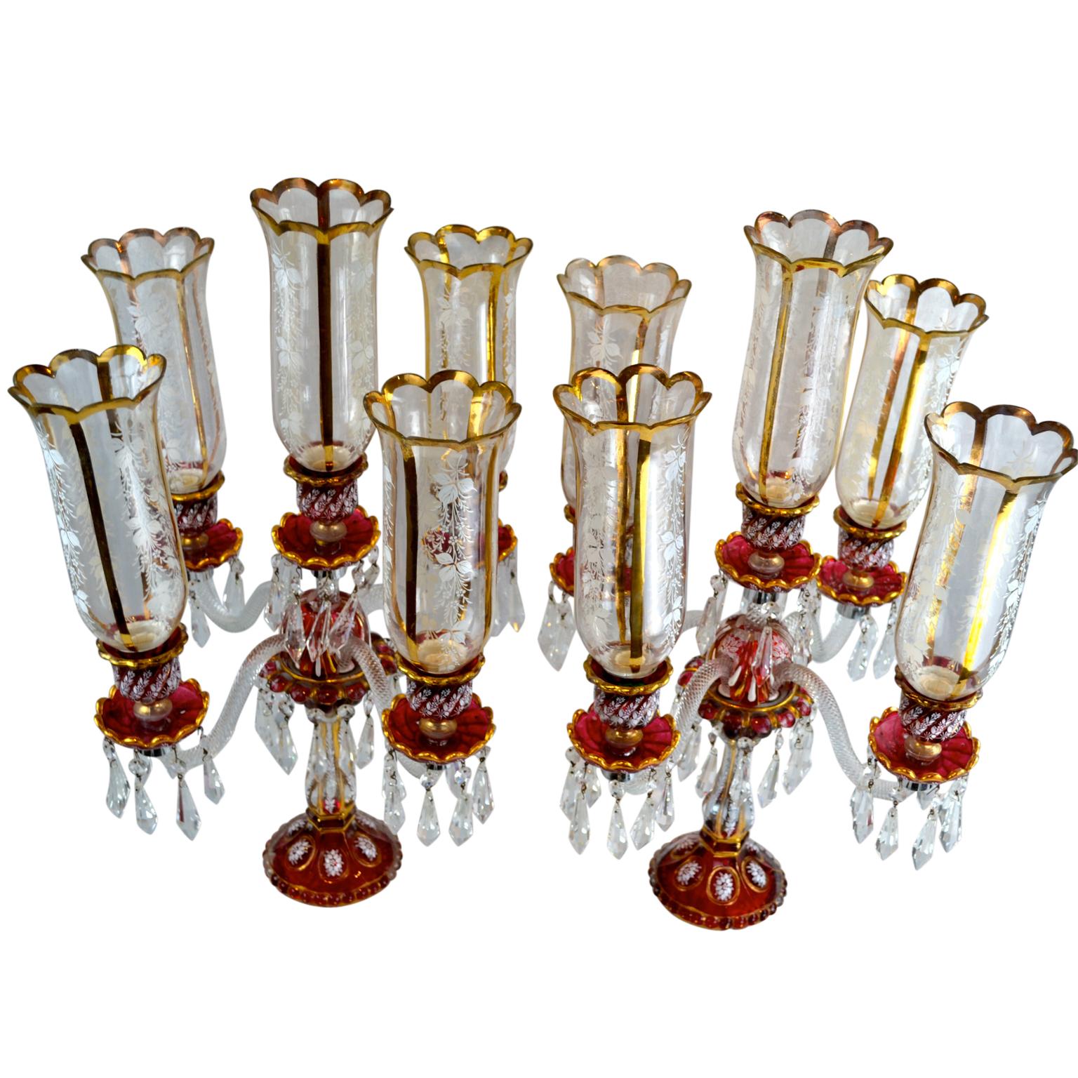 A pair of Baccarat style candelabra; much of the crystal having a ‘ruby wash’ finish and further decorated with white enamel flowers and gilt decoration; the central stem supports four candle arms and a central candle arm, each with a decorated
