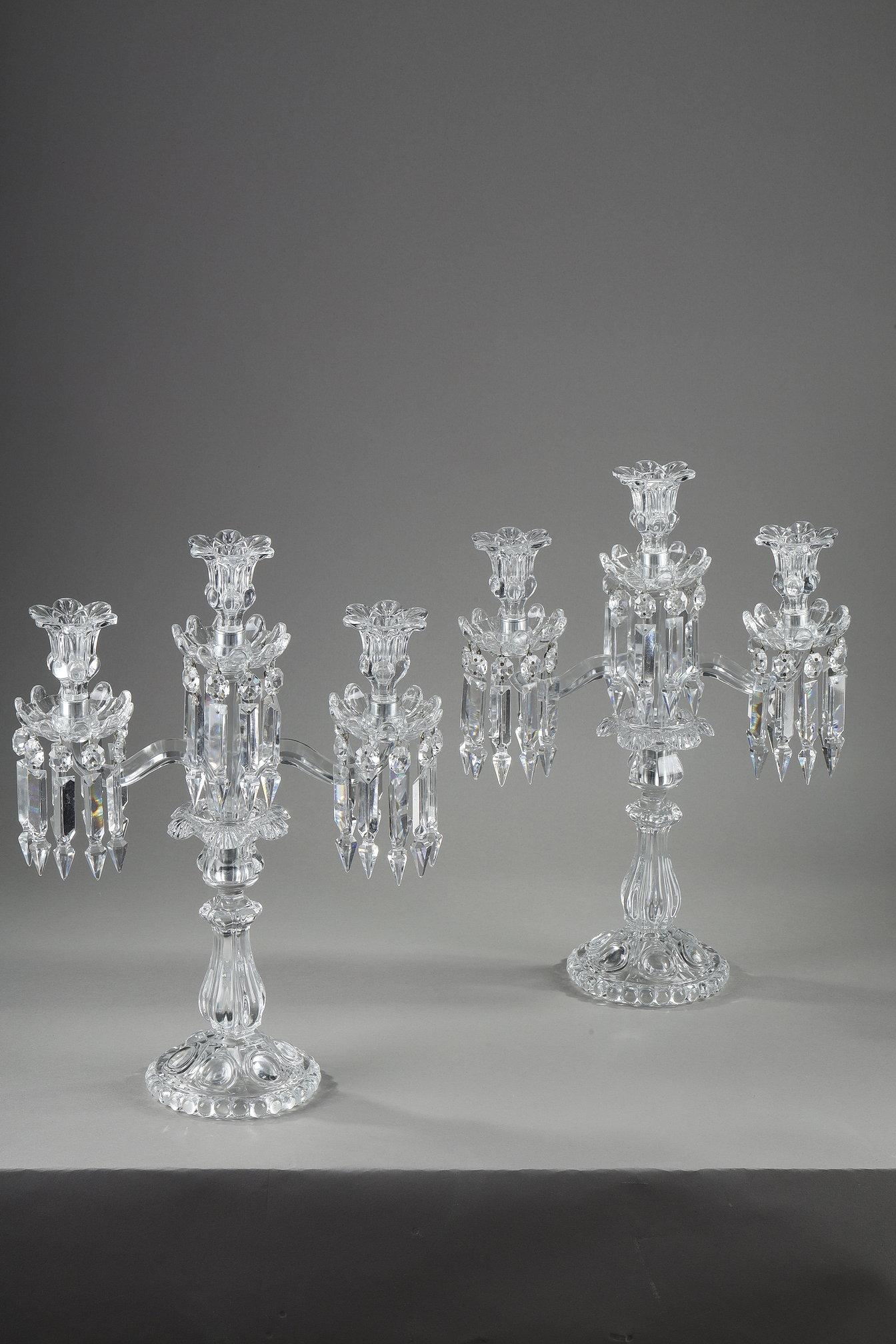 Pair of Baccarat three-light crystal girandoles. They are decorated with geometric crystal pendants, the shafts are ringed and the feet feature gadroon motifs.

This is a 20th-century Baccarat production.

The Baccarat crystal works are