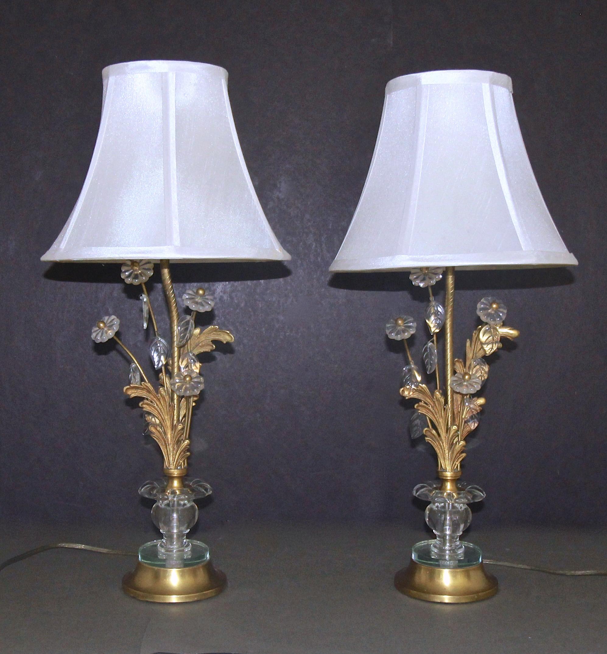 A pair of smaller scale French gilt bronze table or buffet lamps. Decorated with glass rosettes and leaves, and finely crafted foliate embellishments. Base is gilt metal and mirrored glass. Each light uses regular A base bulb. Attributed in Maison