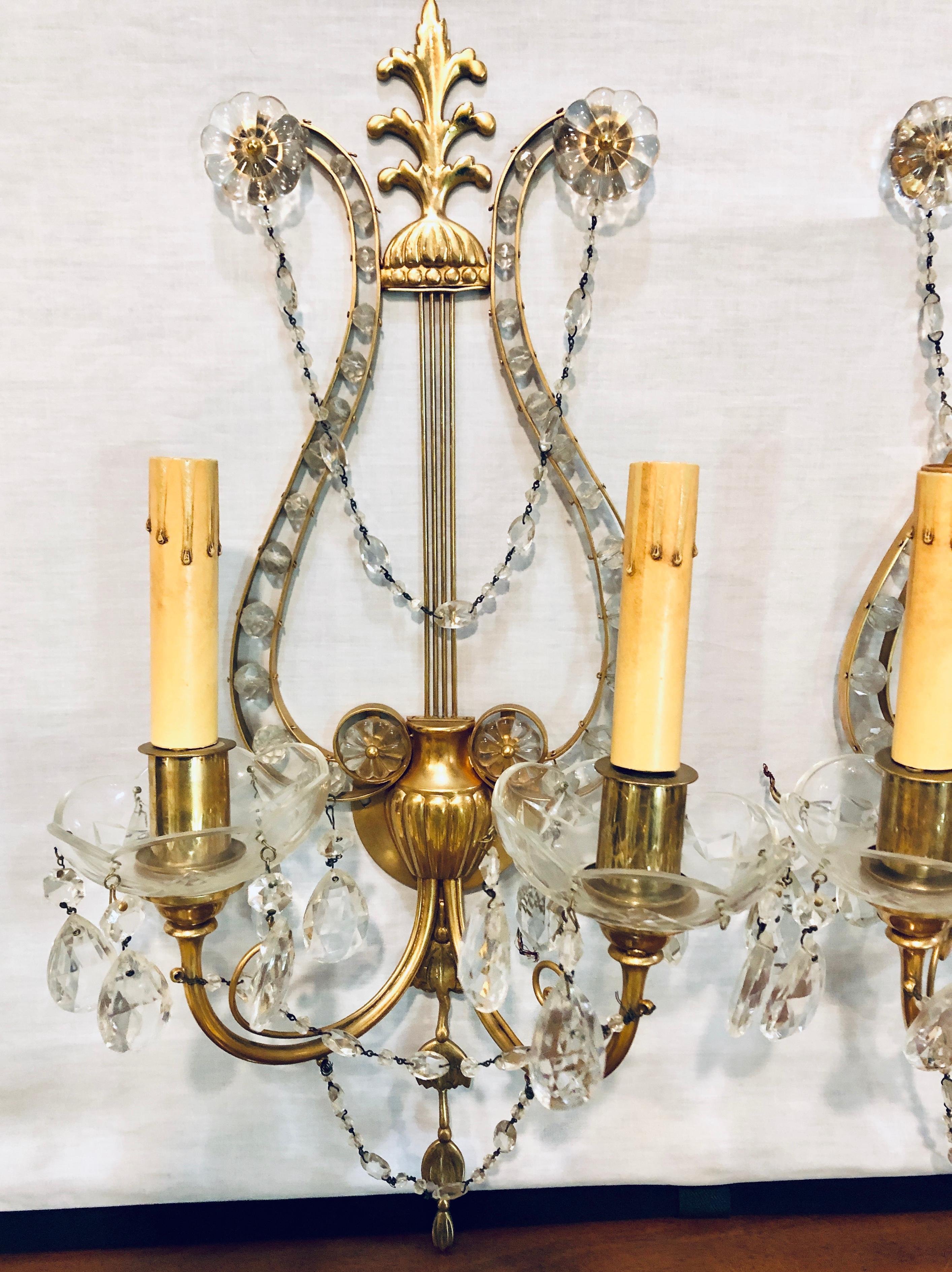 Pair of Bagues style lyre back crystal and brass 2-light wall sconces. These heavy finely cast bronze wall sconce have two lighted arms with flowing crystals and larger rosette crystals throughout. Direct from a Greenwich CT home.