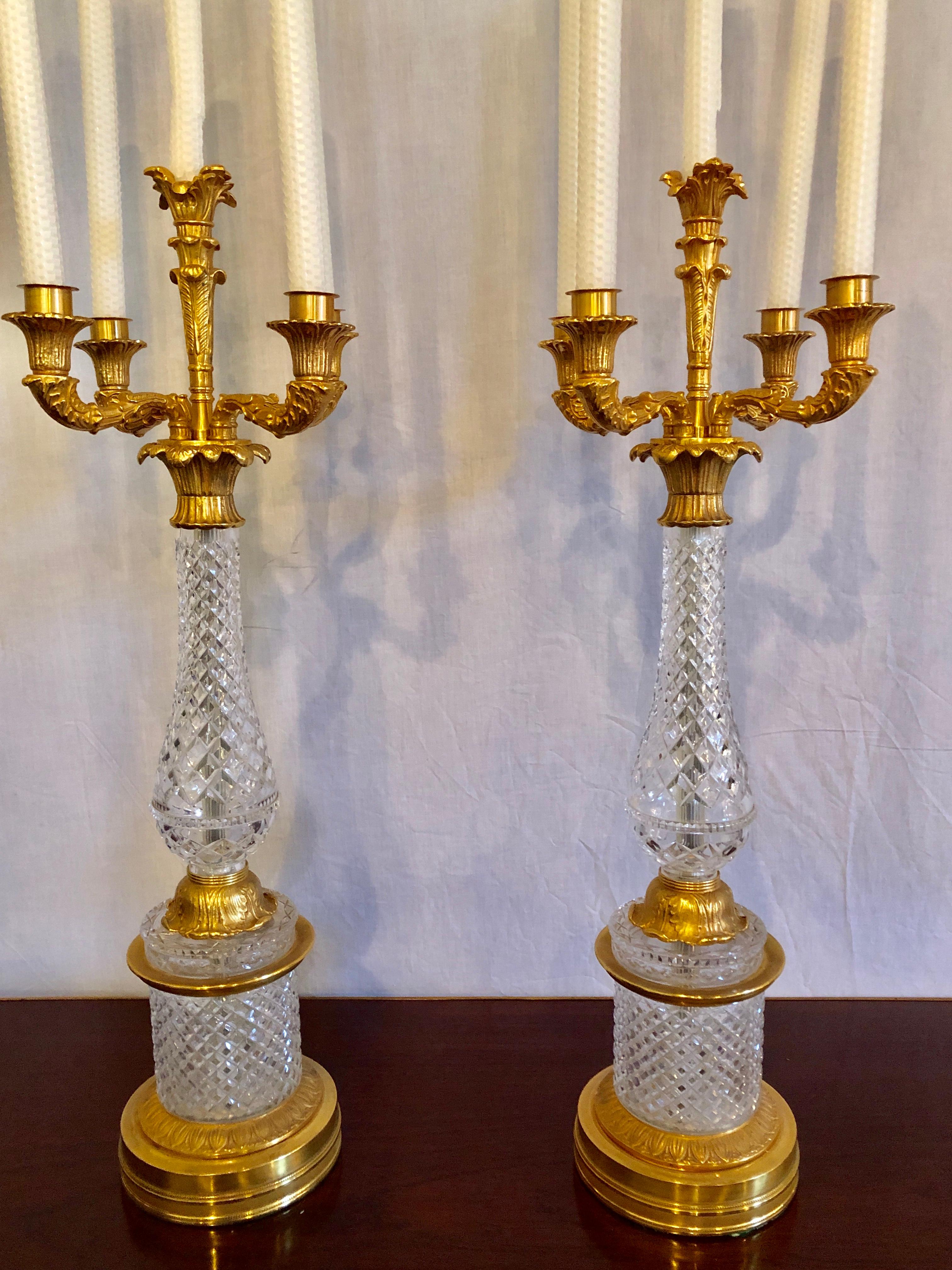 Large and impressive pair of crystal and gilt brass table candelabras. Fine quality circa 1930s. These cut and crafted candelabras can easily be converted into table lamps should the need arise. The Louis XVI style gilt metal is chased in the finest
