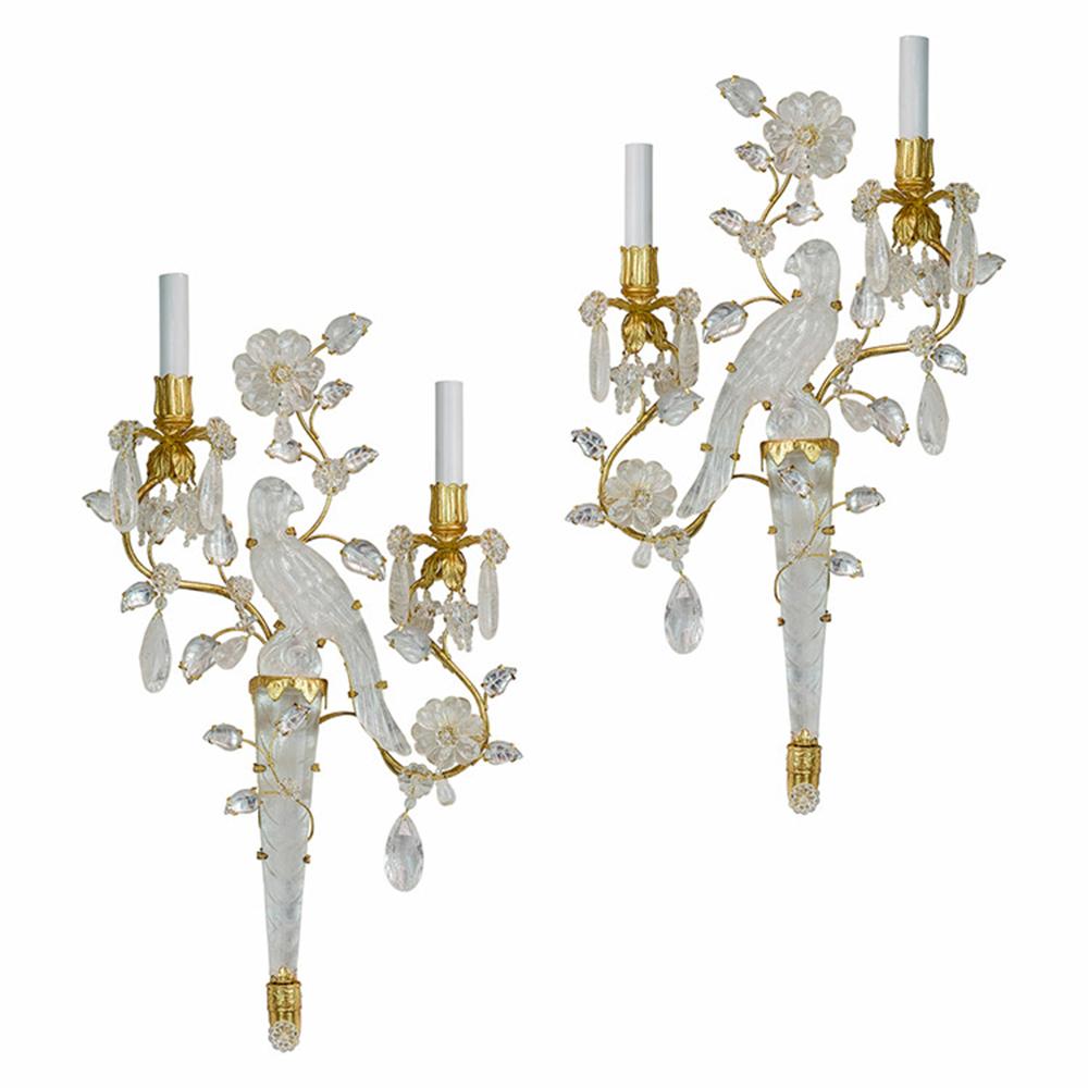 Pair of cut crystal parakeet sconces with gilt bronze branches. Carved crystal parakeet perches on a triangular base with curved branches encircling the central birds. Carved leaves and cut teardrop crystals dapple the branches. A flower with