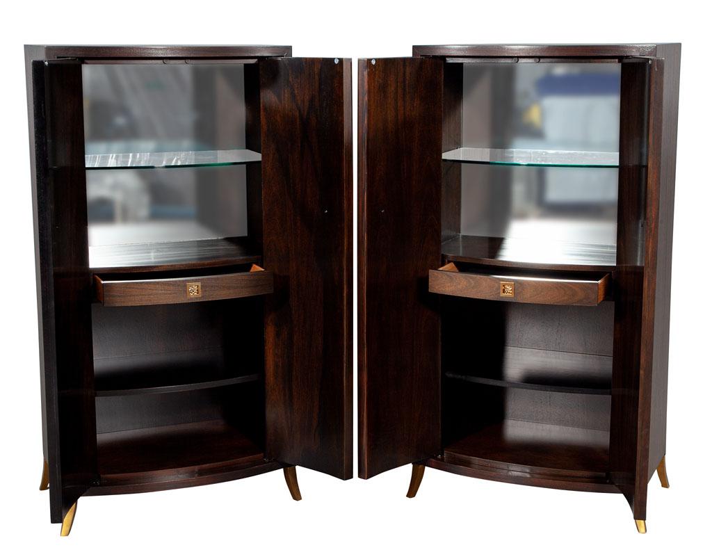 Pair of baker bevel bar cabinets by Thomas Pheasant. Unique curved design with squared detailed fronts. Retrofitted interiors with mirror backing for use as a bar cabinet. Ample storage with large shelves and beautiful curved drawer. Completed with