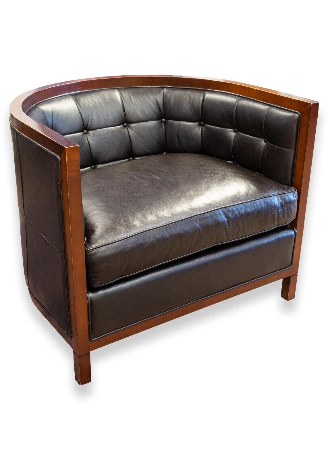 A pair of Baker black leather tufted tub chairs with wood trim. These wonderful accent chairs have a very attractive design including a balanced mix of rounded sides and sharp edges. These chairs feature a dark wood trim and legs, and are