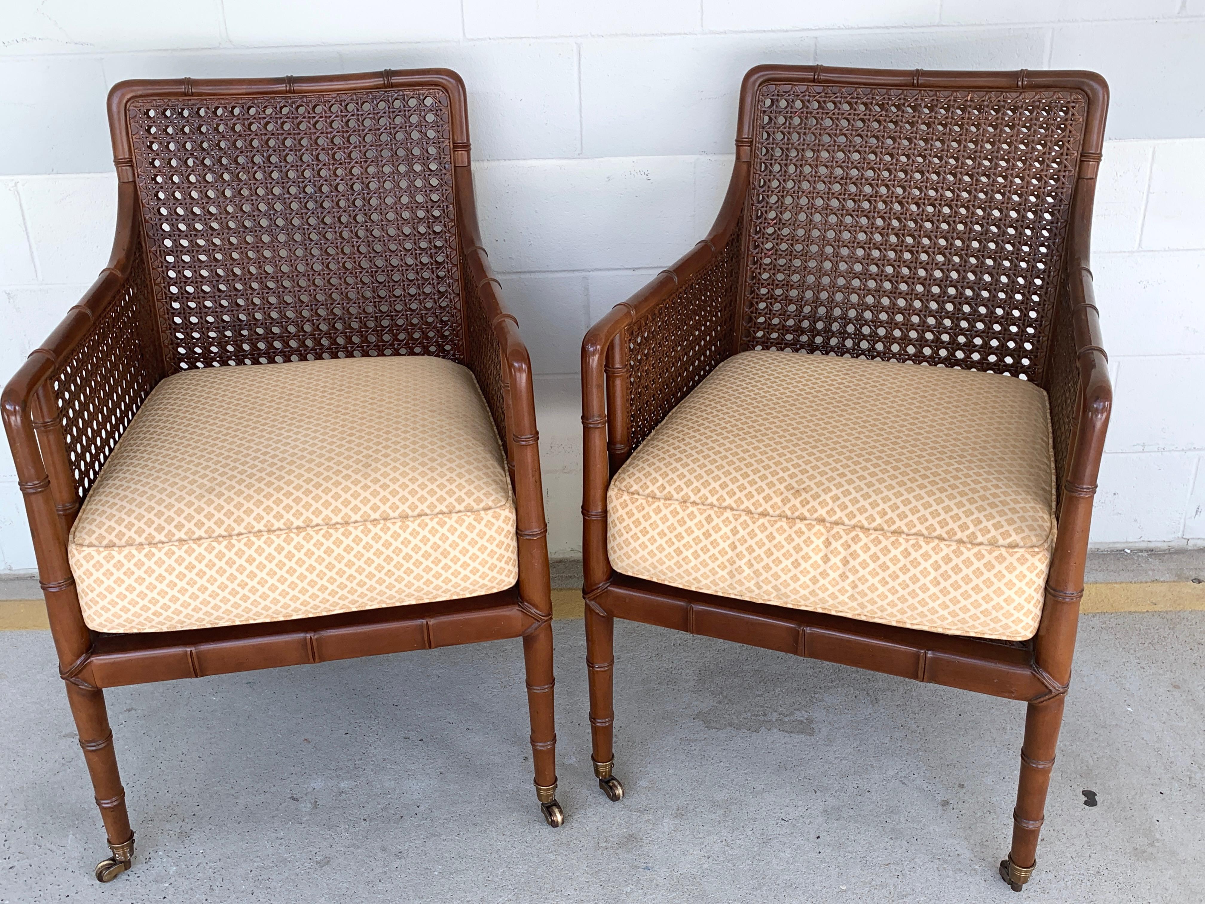 Pair of Baker Faux bamboo caned Campaign style chairs, each one with subtle carved mahogany frames, all-over caning, removable cushions (21