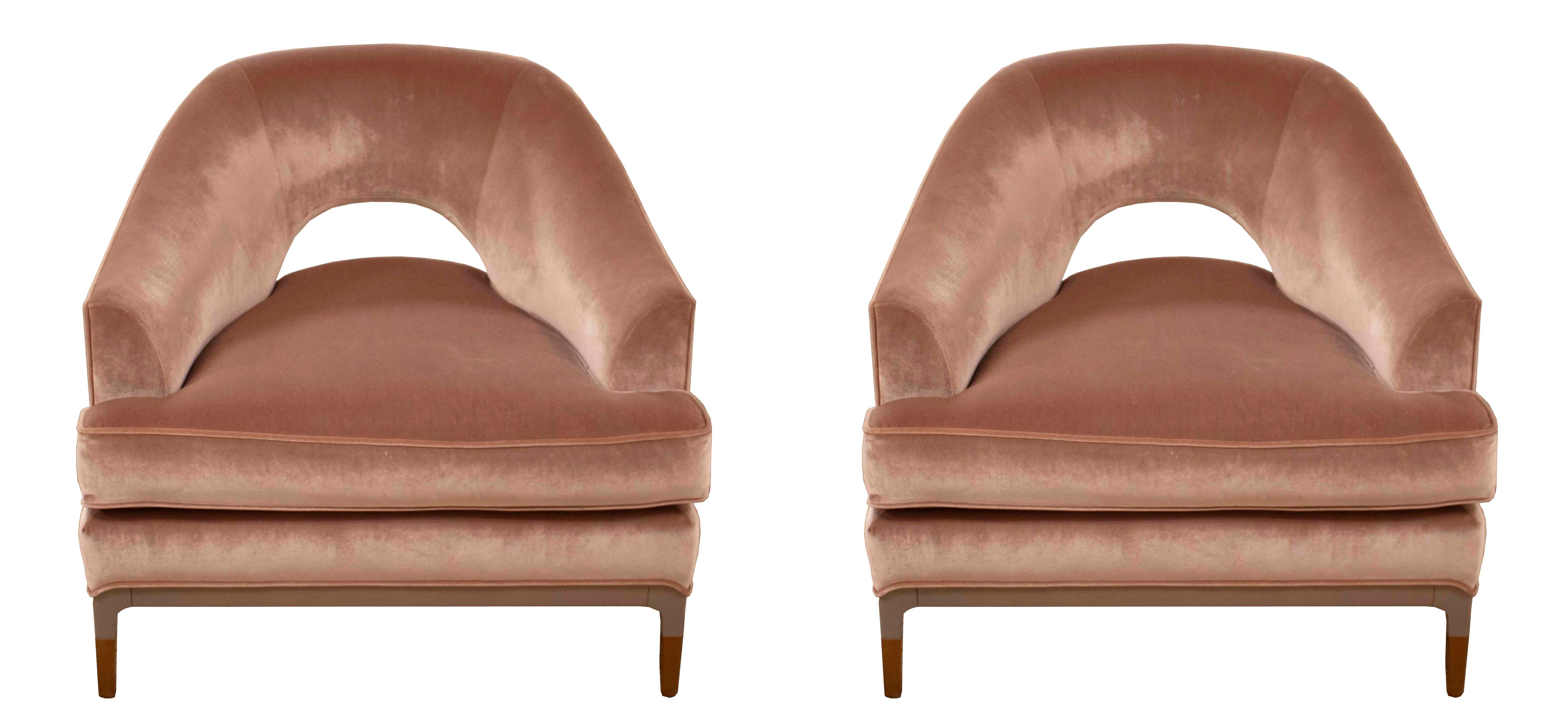 This pair of lounge chairs was designed by Jean-Louis Denoit for Baker and is upholstered in a sophisticated blush velvet with the legs and frame in both a nougat wood and an antique bronze finish. The curved back and attention to detail makes these