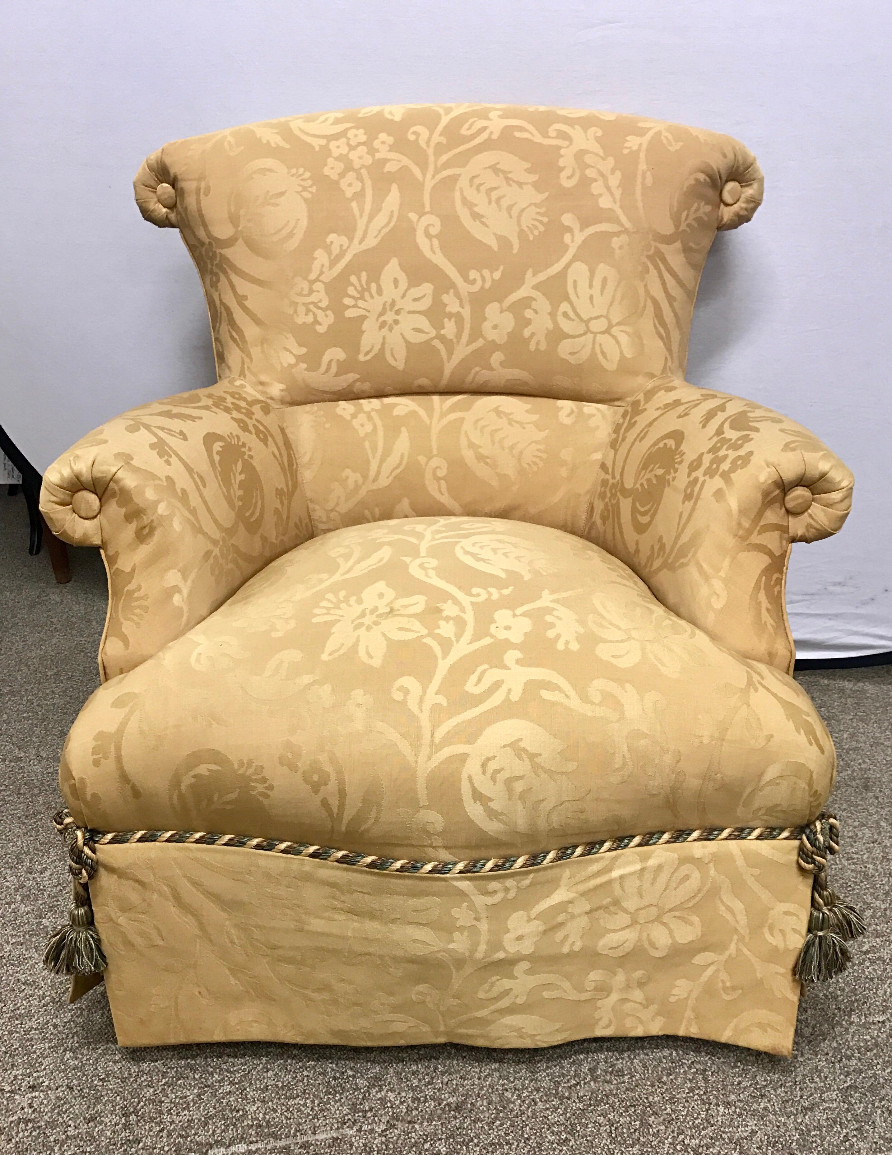 Elegant Baker Furniture wingback armchairs upholstered in a luxurious gold damask fabric with a coordinating rope and tassel detail. 