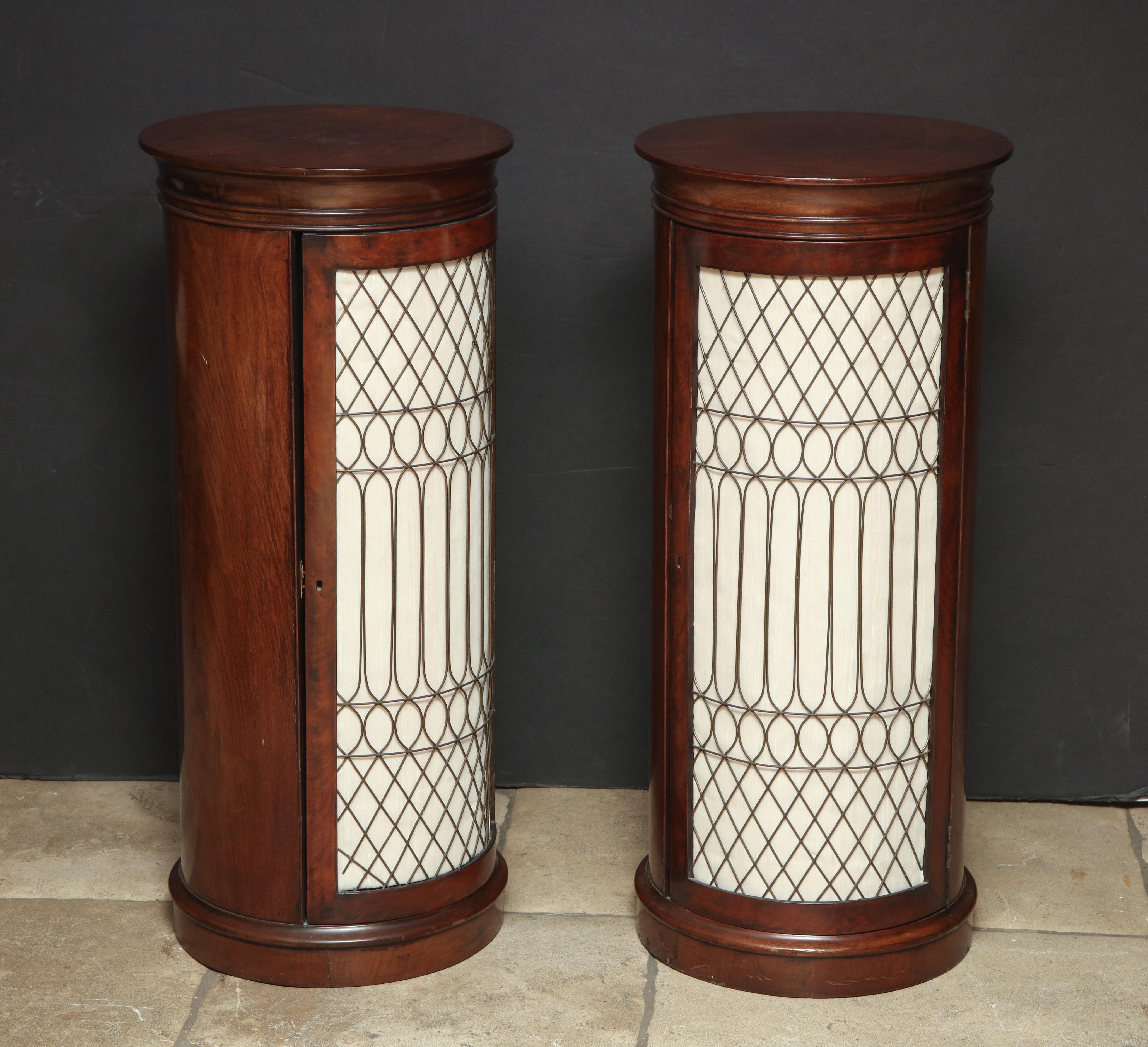 A fine pair of Baltic neoclassic walnut cylinder form cabinet pedestals with brass grills and molded top edge.