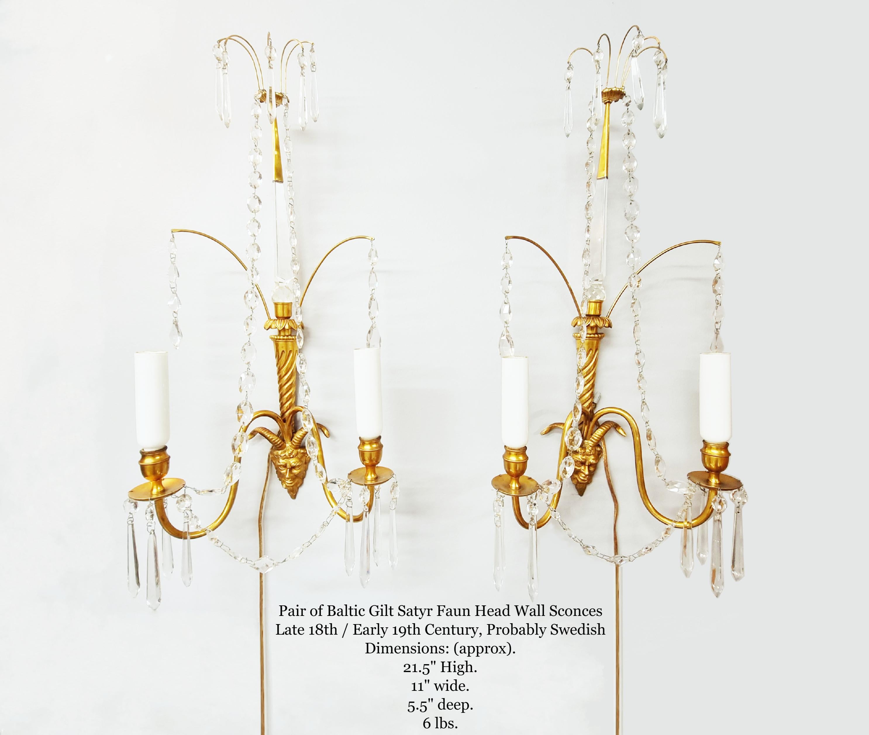 Pair of Baltic Gilt Satyr Faun Head Wall Sconces
Late 19th / Early 20th Century, Probably Swedish

Ball finial to gilt bronze canopy, five scrolls with prism drops, two chains from canopy to bobeches, central triangular crystal upper column