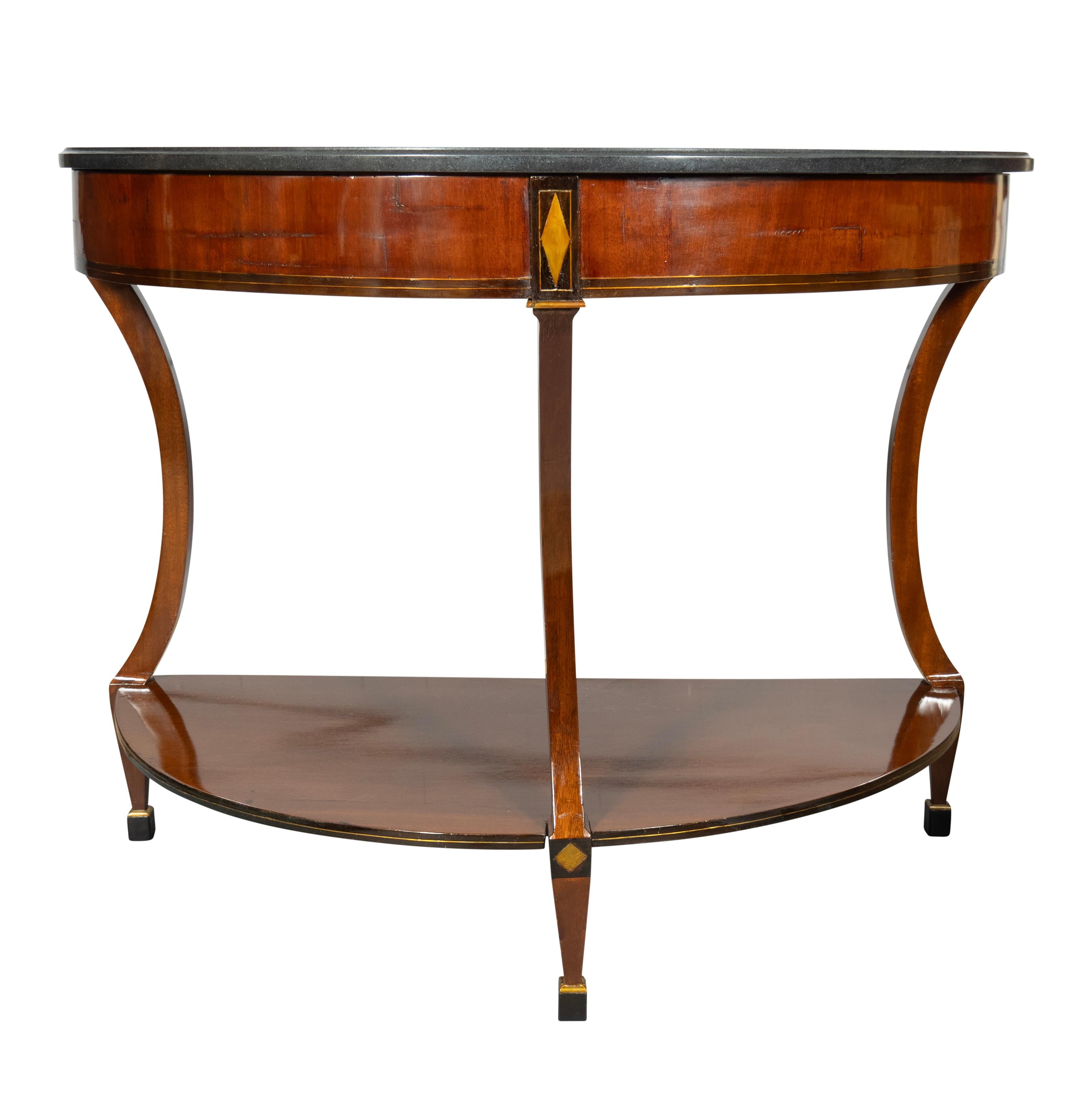 With later black granite tops. Each Demilune shape with mahogany frieze with central diamond form brass inlay. Curved legs joining a lower conforming shelf. Square ebonized block feet. Provenance ; HM Luther Antiques at the Carlyle Hotel. Original