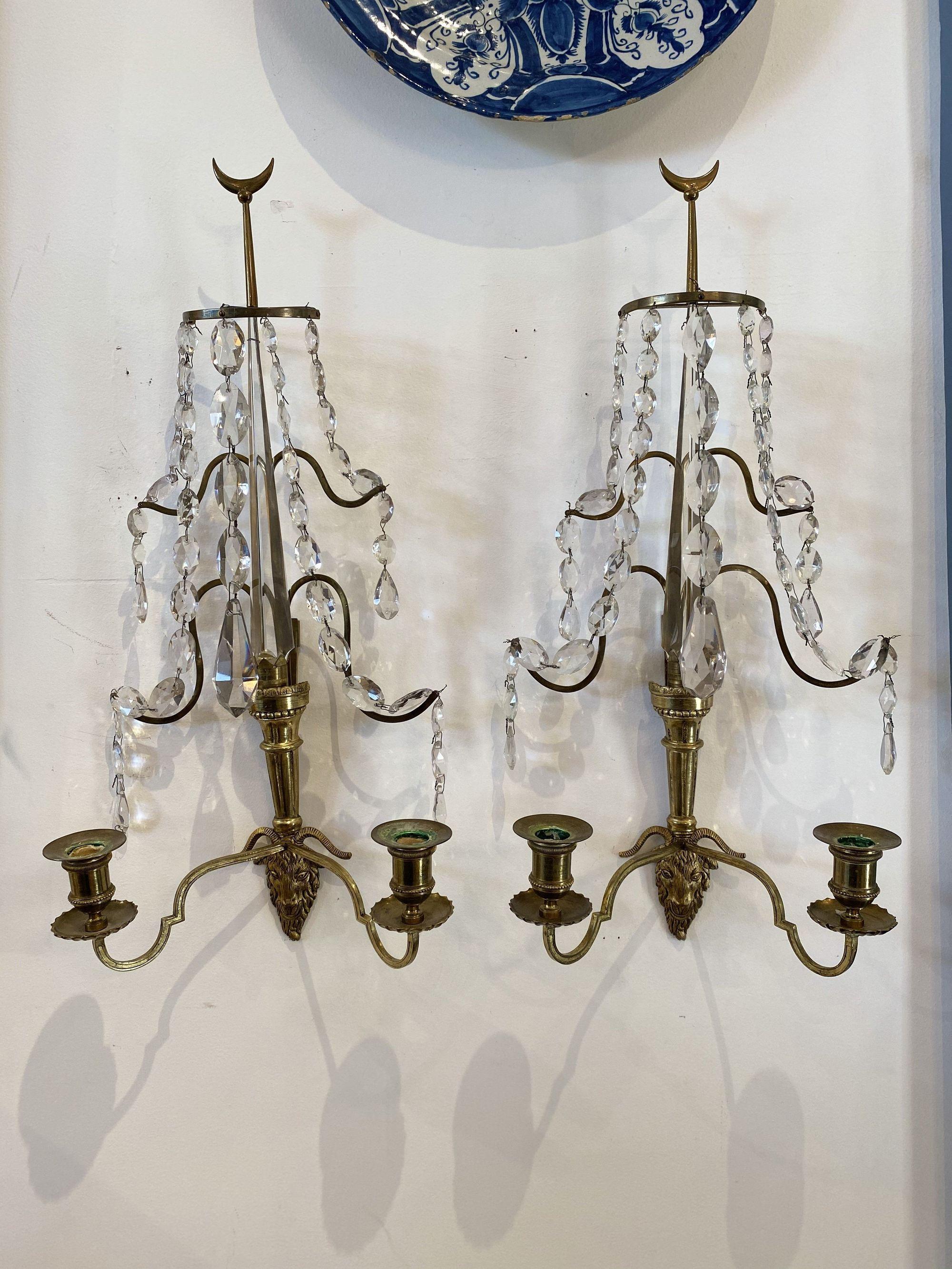 Pair of Baltic or Russian fire gilt bronze two-arm wall sconces, circa 1810, with crystal festoon design, goat head termination, having a magnificent central crystal spear and a half moon form finial top. From the collection of renowned Washington