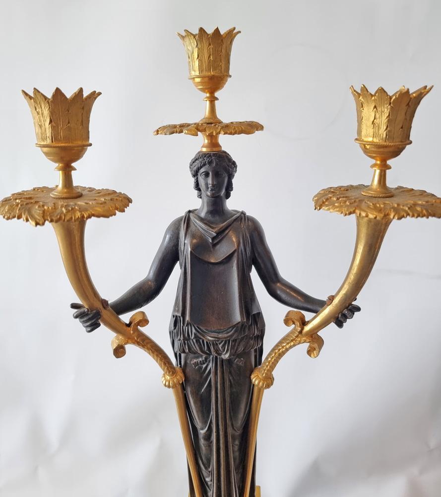 A very fine and dramatic pair of early 19th century patinated bronze and ormolu figural candelabra. Standing upon square ormolu bases with applied ormolu mounts the patinated bronze figure of a woman in classical dress holds up three candle holders.