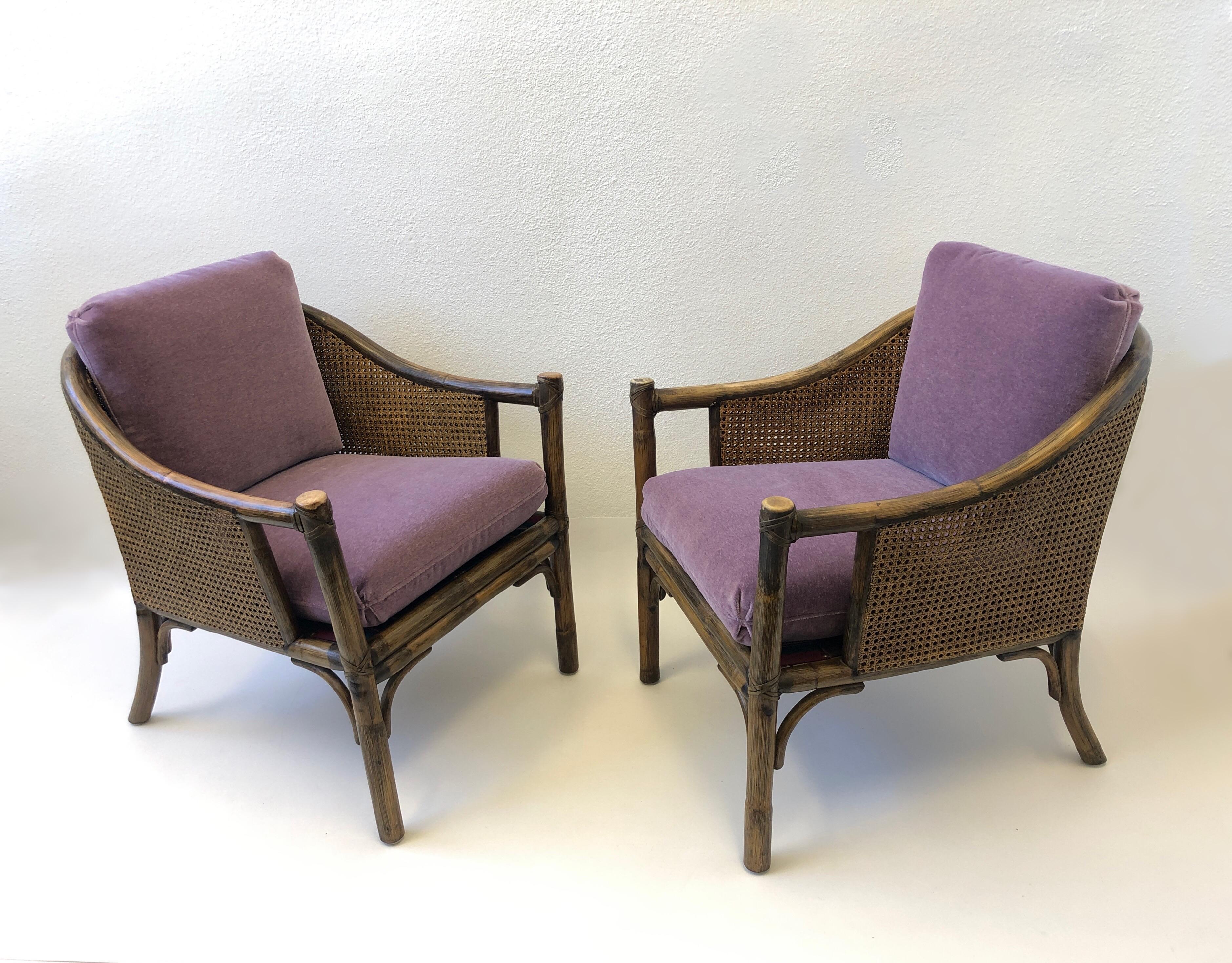 A beautiful dark stain bamboo frame and double cane sides lounge chairs designed in the 1970s by McGuire. The chairs frame is in original condition, some wear on the arms. New lite purple soft mohair cushions. Both chairs retain the brass McGuire