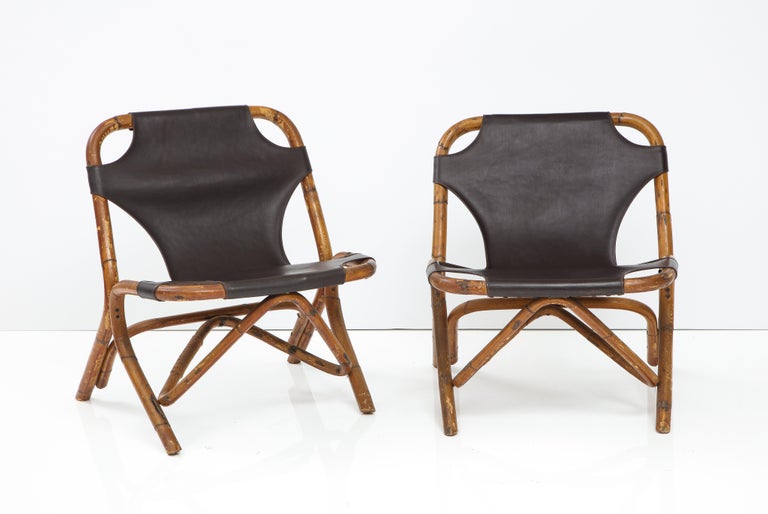 Rare and unique pair of Italian Mid-Century Modern bamboo or rattan and leather sling chairs attributed to designer Tito Agnoli for Bonacina, Italy, 1960s.  In very good vintage condition.  Leather has wrap around stitching and is dark coffee brown