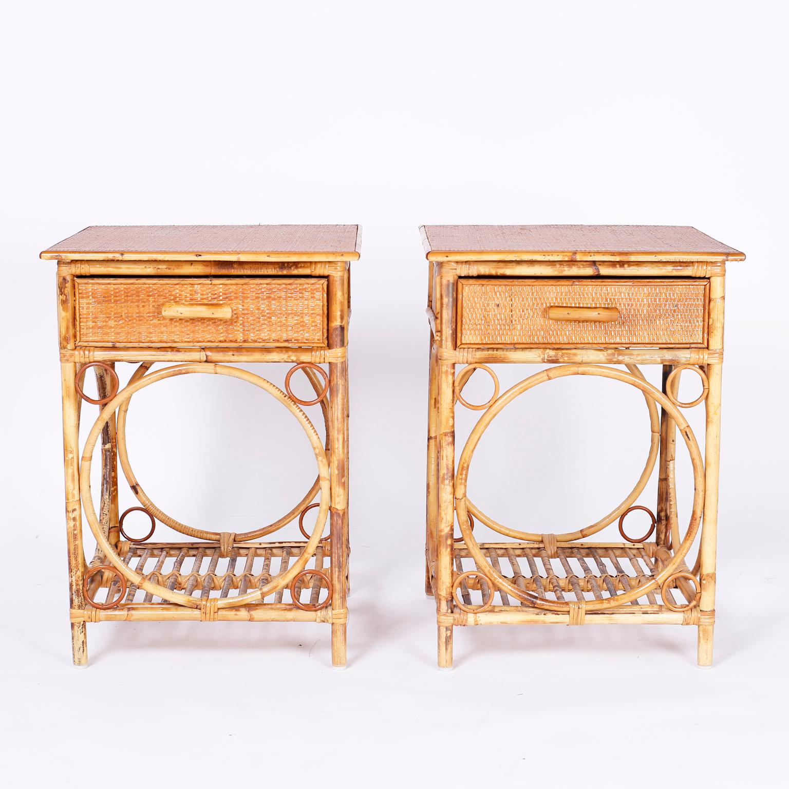 Pair of British Colonial nightstands or end tables with grass cloth on the tops and drawer fronts. The bases feature a bent bamboo technique that highlights the open storage space.