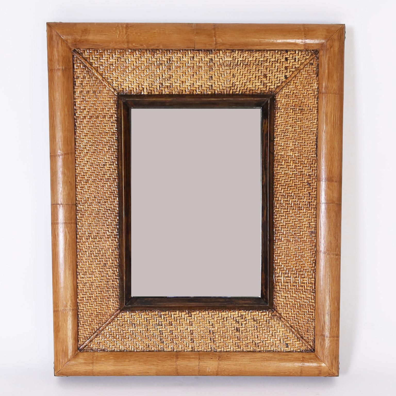 Standout pair of British colonial style wall mirrors featuring a bamboo frame with campaign style clips on the corners, grasscloth mats, faux tortoise inner frame, and beveled glass mirrors.
