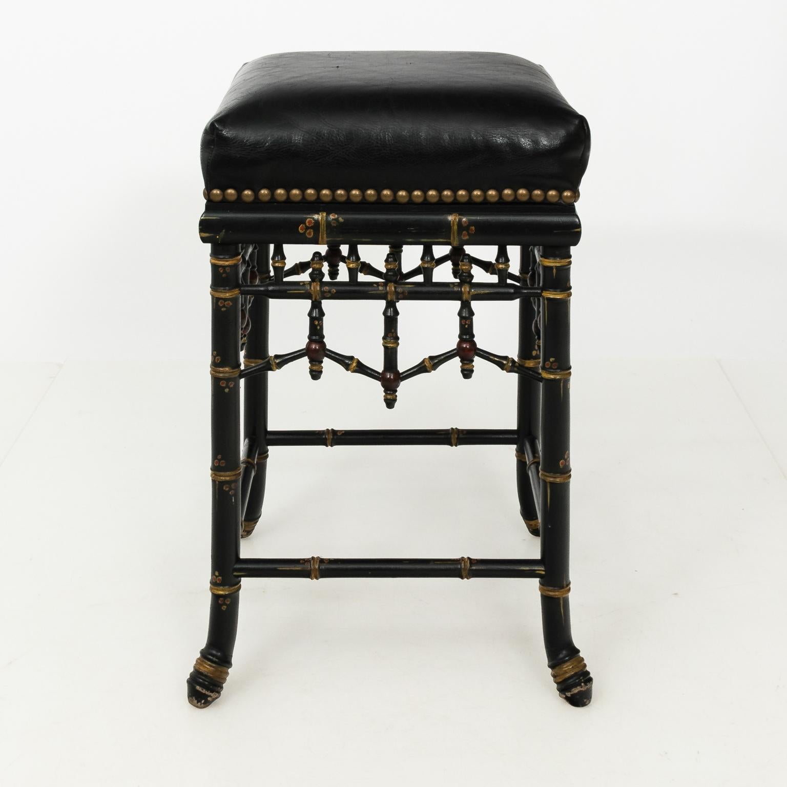 Pair of Eastlake style black painted Bamboo bar stools with leather upholstered seats, circa 20th century. These stools also feature nail head trim, turned spindles, and a box stretcher.
   