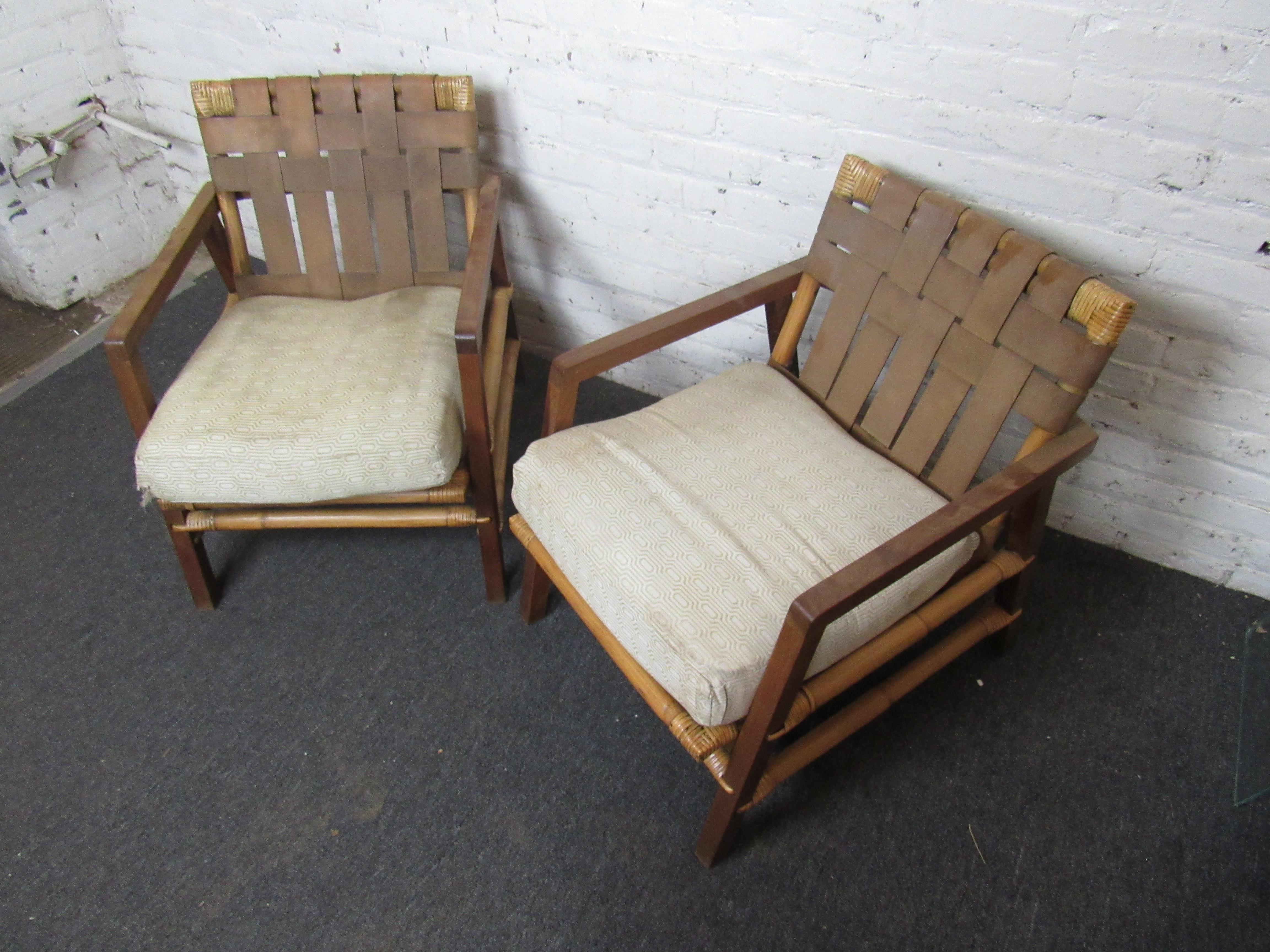 An incredible pair of lounge chairs showing off a frame of teak and bamboo, with woven backs and upholstered seat cushions. Please confirm item location with seller (NY/NJ).
