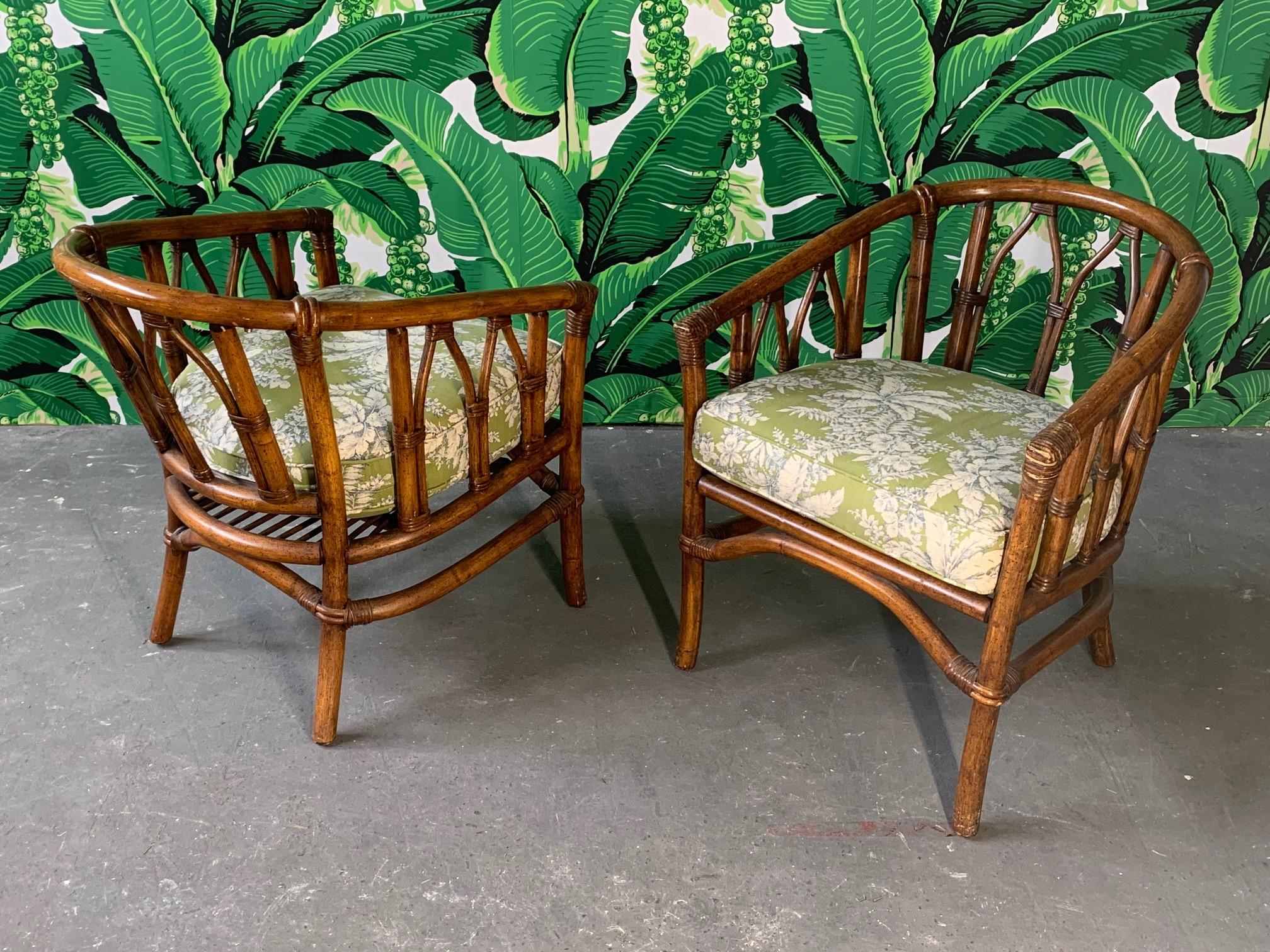 Pair of bamboo accent chairs finished in deep brown with a tropical print upholstery. Includes seat and back cushions. Very good vintage condition with only minor imperfections consistent with age.