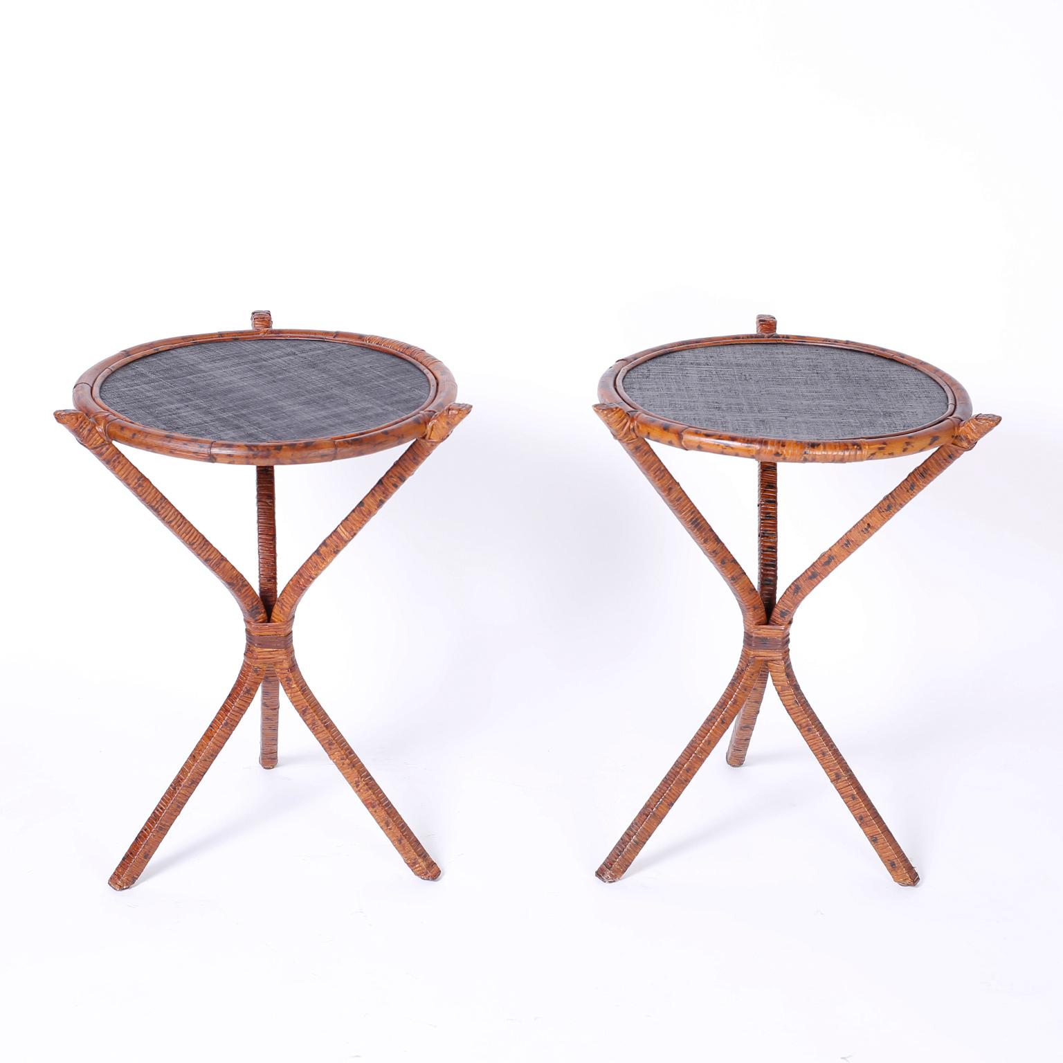 British colonial style stands with round tops framed with bent bamboo around a grasscloth surface. The bases are reed or wicker wrapped around a metal frame with a faux burnt bamboo finish. We have another pair of these tables, if 4 is required.