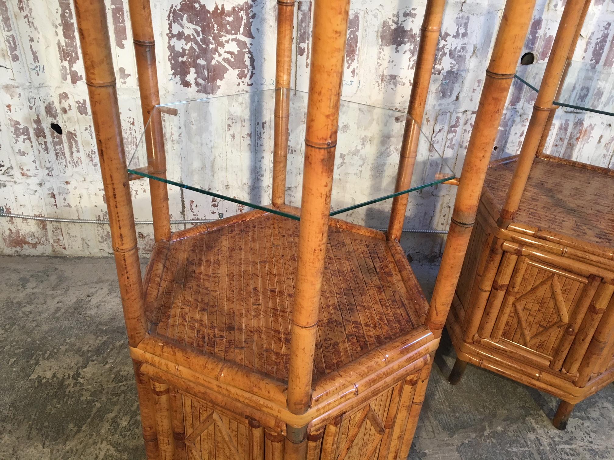 Fabulous pair of large bamboo pagoda style étagères, circa 1950s. Hexagon shape with glass shelving and storage below. Excellent condition, only very minor signs of age appropriate wear. Doors operate perfectly. Glass shelves in excellent condition.