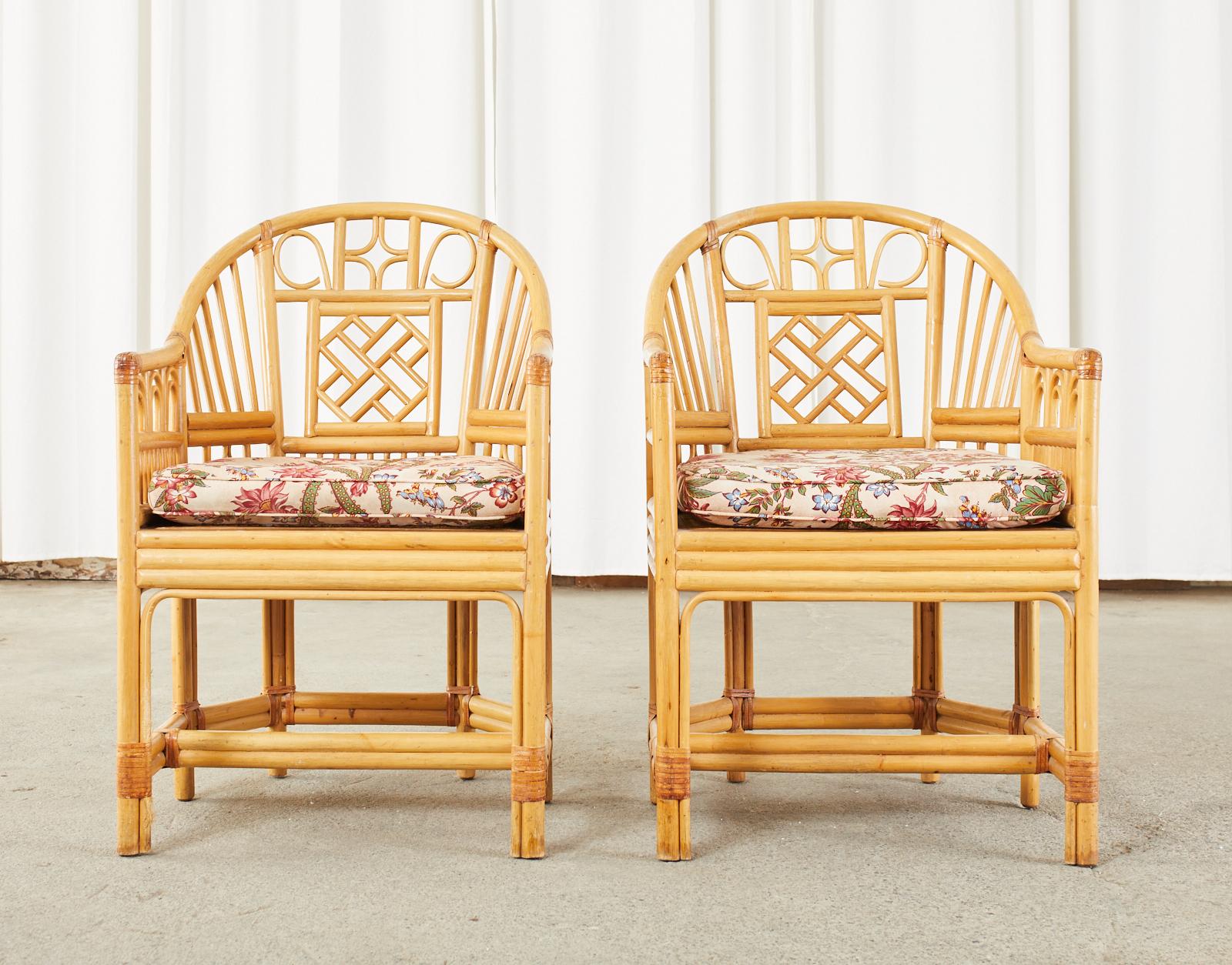 Distinctive pair of bamboo rattan barrel back armchairs made in the grand Brighton pavilion style. The mid-century chairs feature a bamboo rattan frame with decorative Chinese Chippendale style open fretwork designs. The chairs have a caned seat and