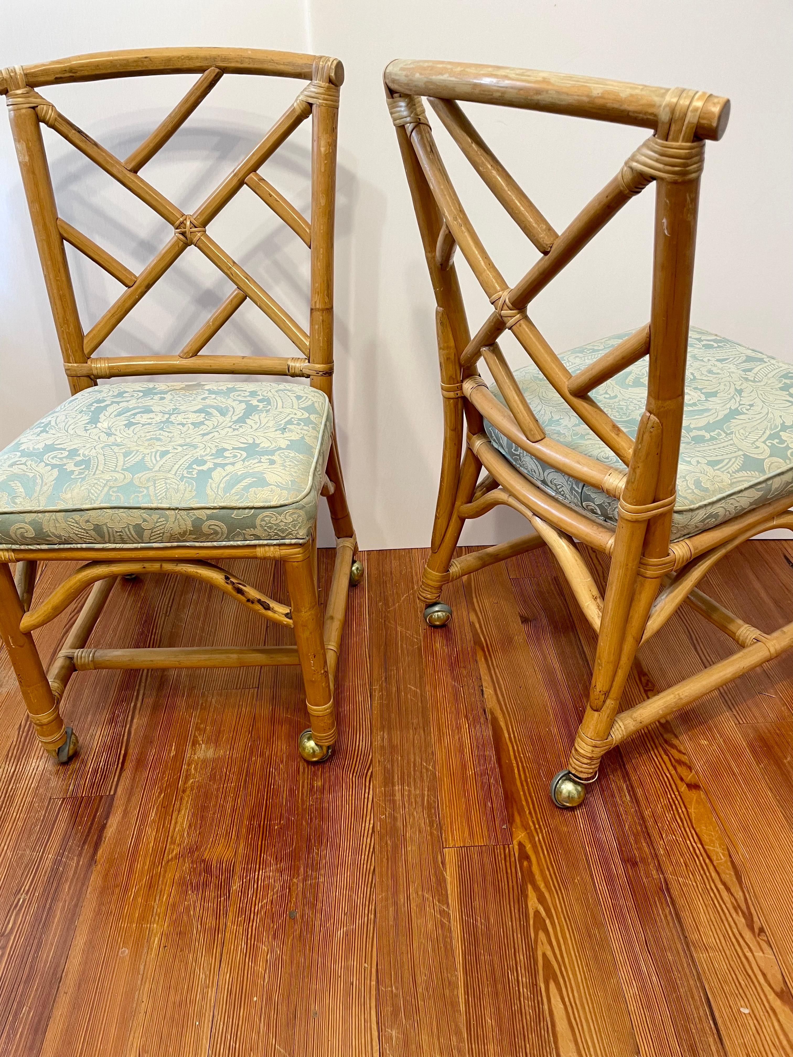 Pair of Rattan Bamboo side chairs on casters with upholstered seats. Good overall vintage condition, with some wear to finish and upholstery. Seats remove easily for re upholstery which should be done due to some wear and stains.