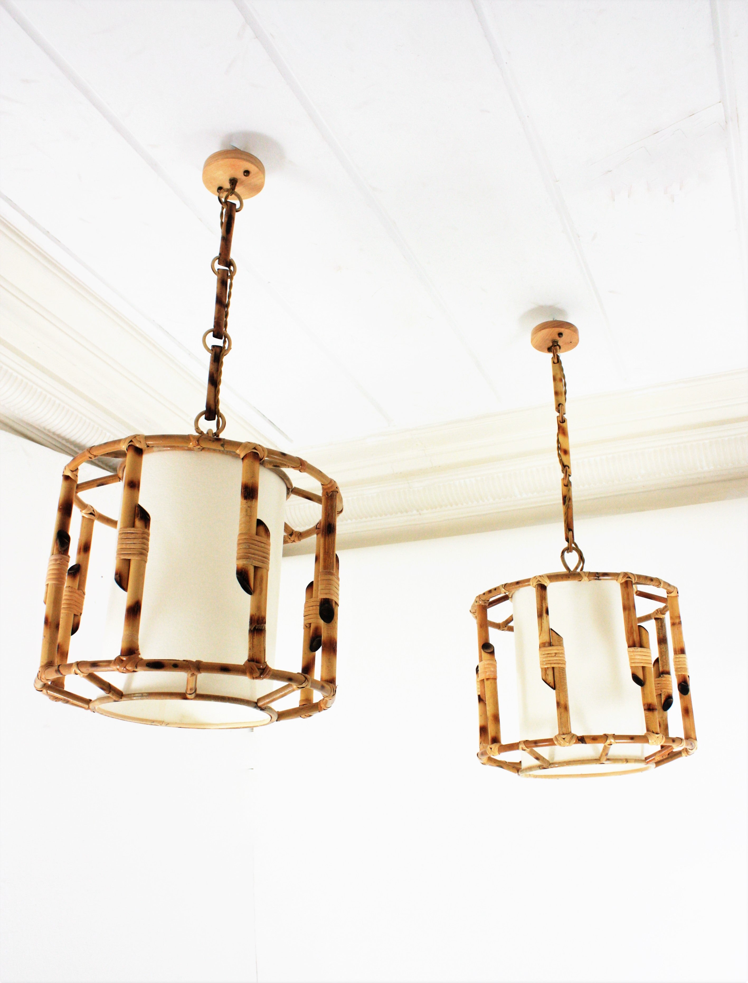A cool pair of handcrafted rattan drum shaped ceiling suspension lamps with inner paper lampshades. France, 1960s
These large lanterns have an eye-catching design featuring a cylindrical bamboo structure with a paper lampshade to diffuse the
