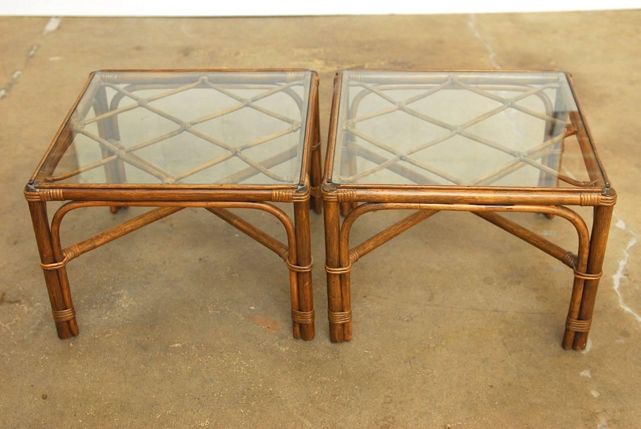 Organic modern pair of side or end tables by Brown Jordan constructed from bamboo and rattan. Featuring an open fretwork lattice top covered with a pane of glass. Supported by four legs conjoined with an X-form stretcher. Other matching pieces also
