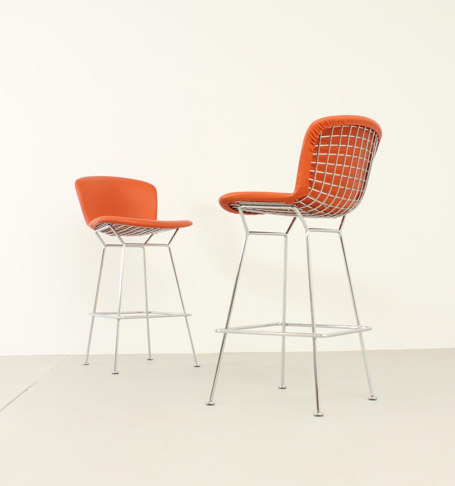 Pair of bar stools designed in 1952 by Harry Bertoia for Knoll, USA. Fully upholstered version in orange leather and polished chrome steel bases. Signed.