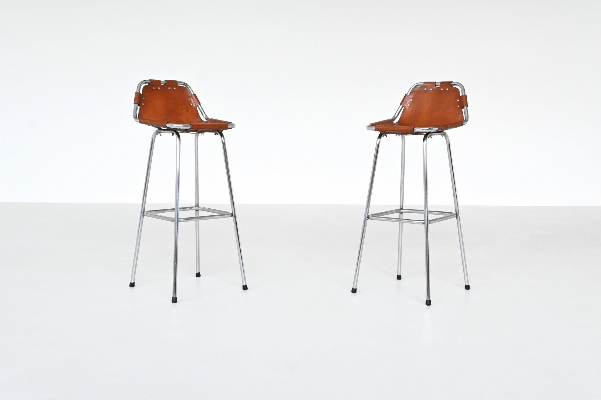 Beautiful shaped pair of beautiful shaped bar stools used by Charlotte Perriand for Les Arcs ski resort, France 1960. These iconic stools feature an elegant combination of rustic charm and industrial strength. The seats are crafted from patinated