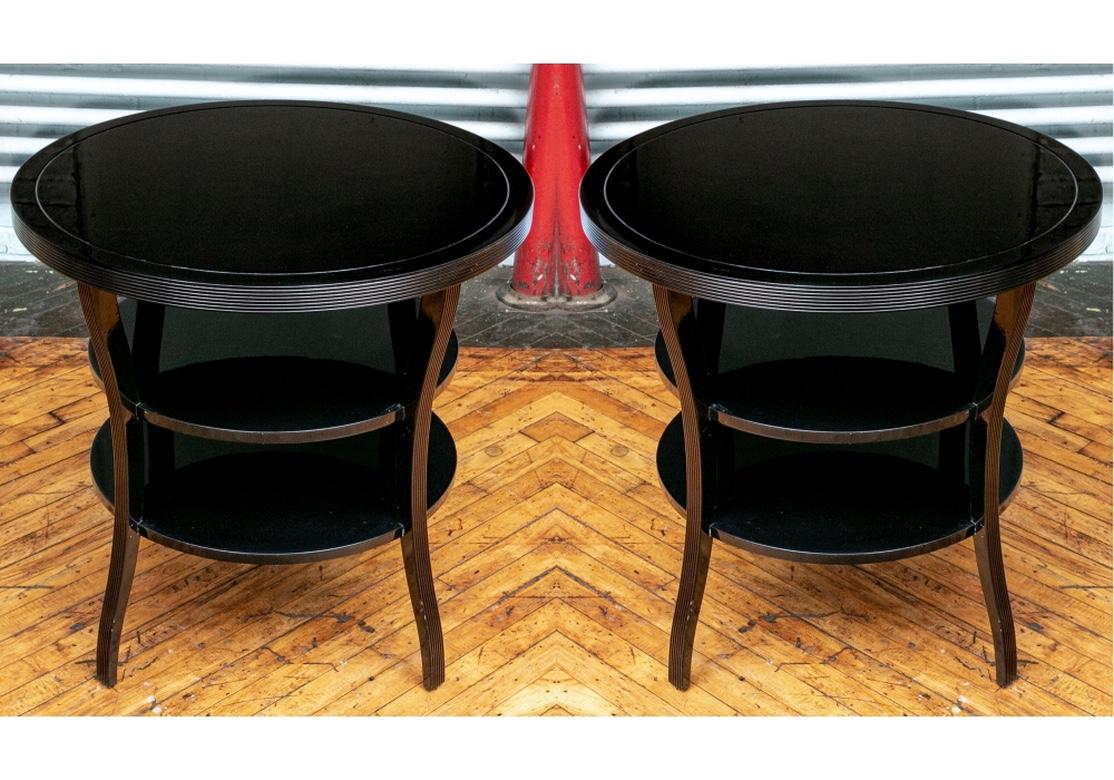 Classic Barbara Barry for Baker pair of tiered end tables in a custom black lacquer treatment. With ribbed top edges and two circular tiers. All raised on four square ribbed curved legs. 
Measures: Diameter 30