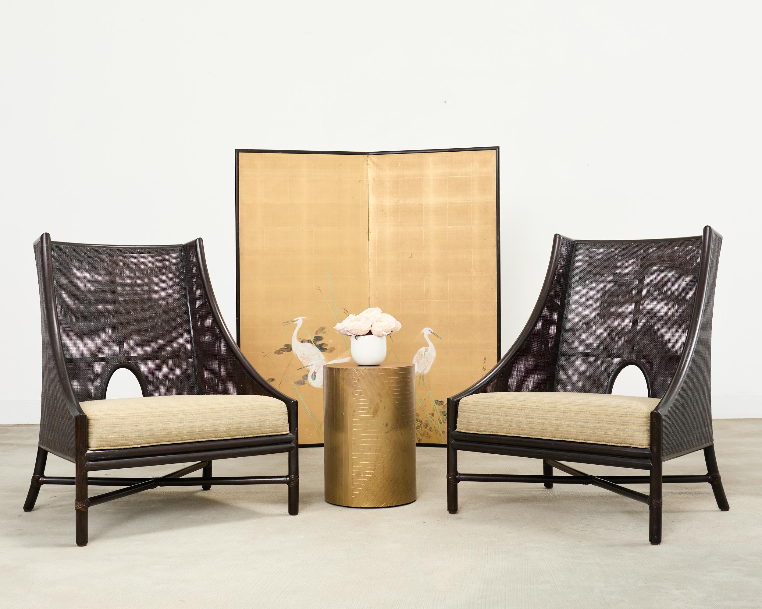 Elegante e rara coppia di grandi sedie o poltrone club con pouf disegnate nello stile moderno organico costiero della California da Barbara Barry per McGuire. Le sedie sono caratterizzate da una struttura in rattan graziosamente curvata, con una
