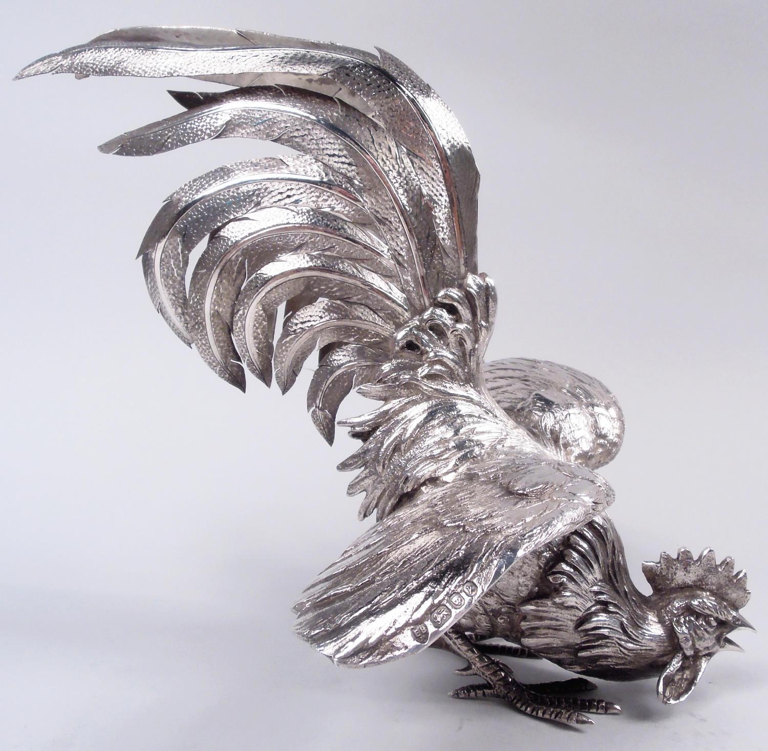 Pareja de aves de plata de ley Isabel II. Fabricado por Edward Barnard & Sons en Londres en 1965. Dos gallos con coronas, barbas y flamantes colas con volantes. Uno tiene una garra levantada y mira hacia abajo, mientras que el otro se acobarda.