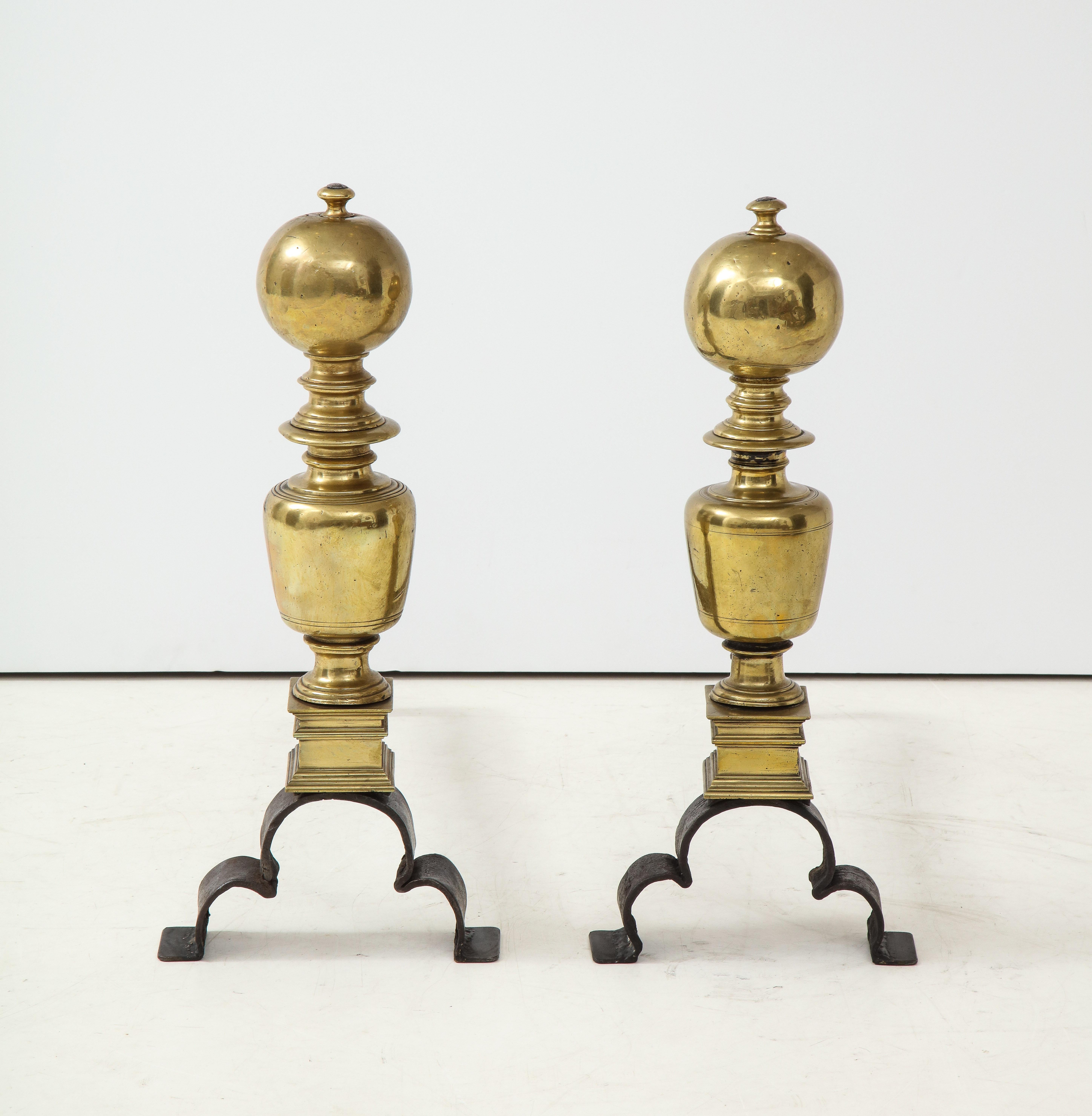 Good pair of bold brass and wrought iron andirons, the ball finials with nipple tops, over balustrade form bodies with squared bases, standing on quatrefoil arched wrought iron legs.





Measures: 21-1/2 x 9-1/2 x 25-1/4 in.