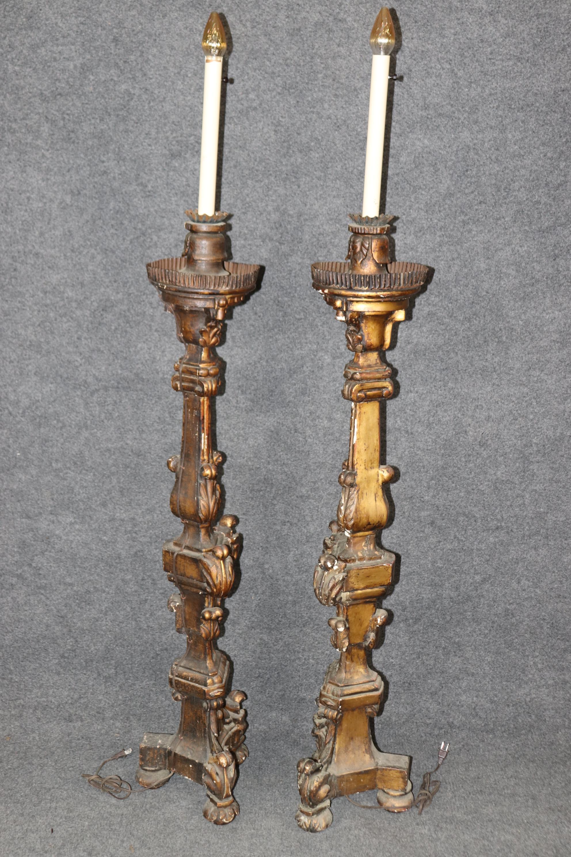 Il s'agit d'une paire de chandeliers baroques italiens en bois doré et en métal qui ont été transformés en lampadaires. Ils sont en mauvais état, avec des éclats et de petites zones de perte de feuilles d'or, ainsi qu'une patine vieillie et