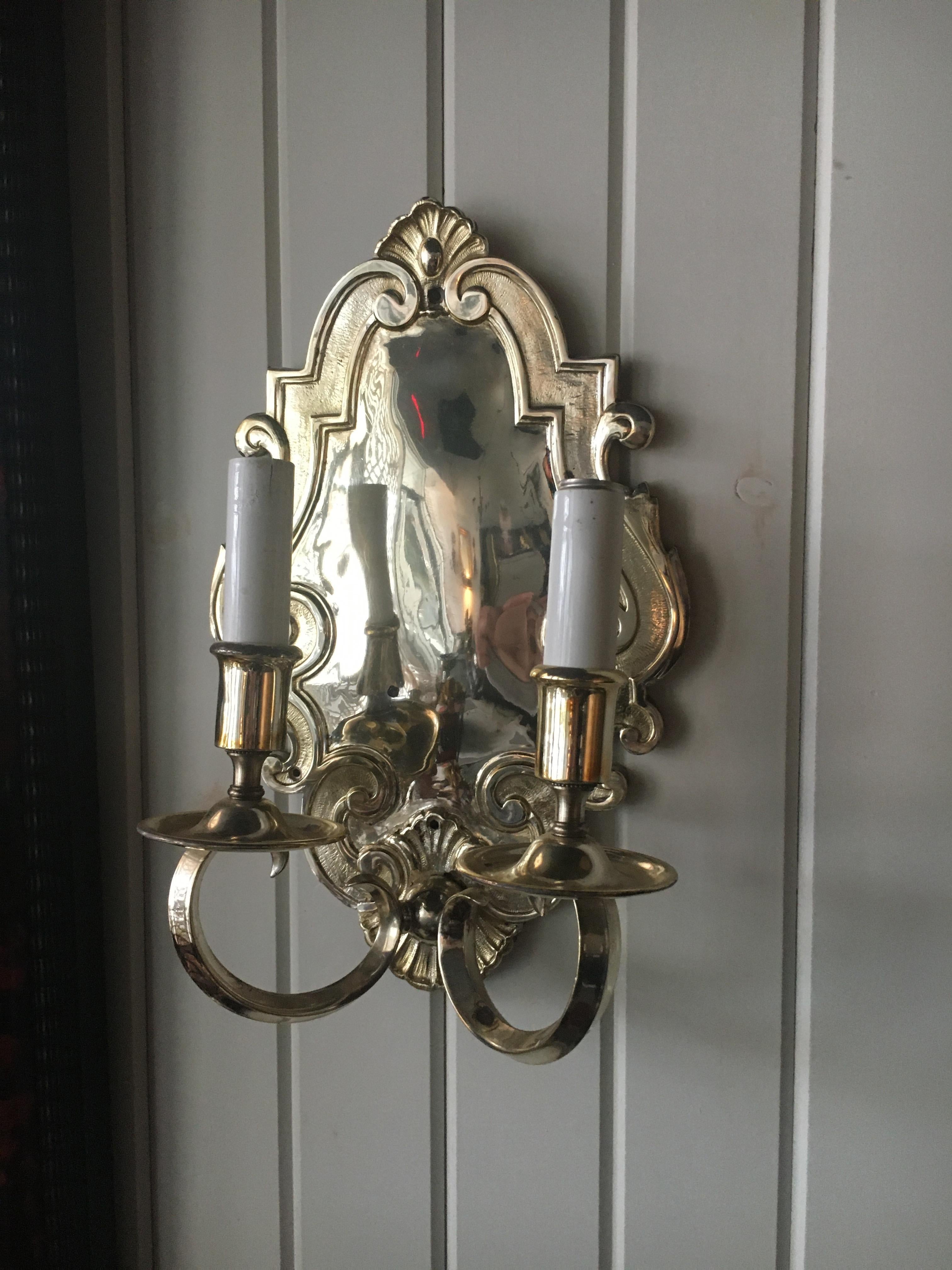 A pair of baroque style silver plated metal two-light wall sconces. Measures: Height 15 inches.  Great scale.  Feel free to call or email with further questions.  They have been sealed so they do not tarnish.