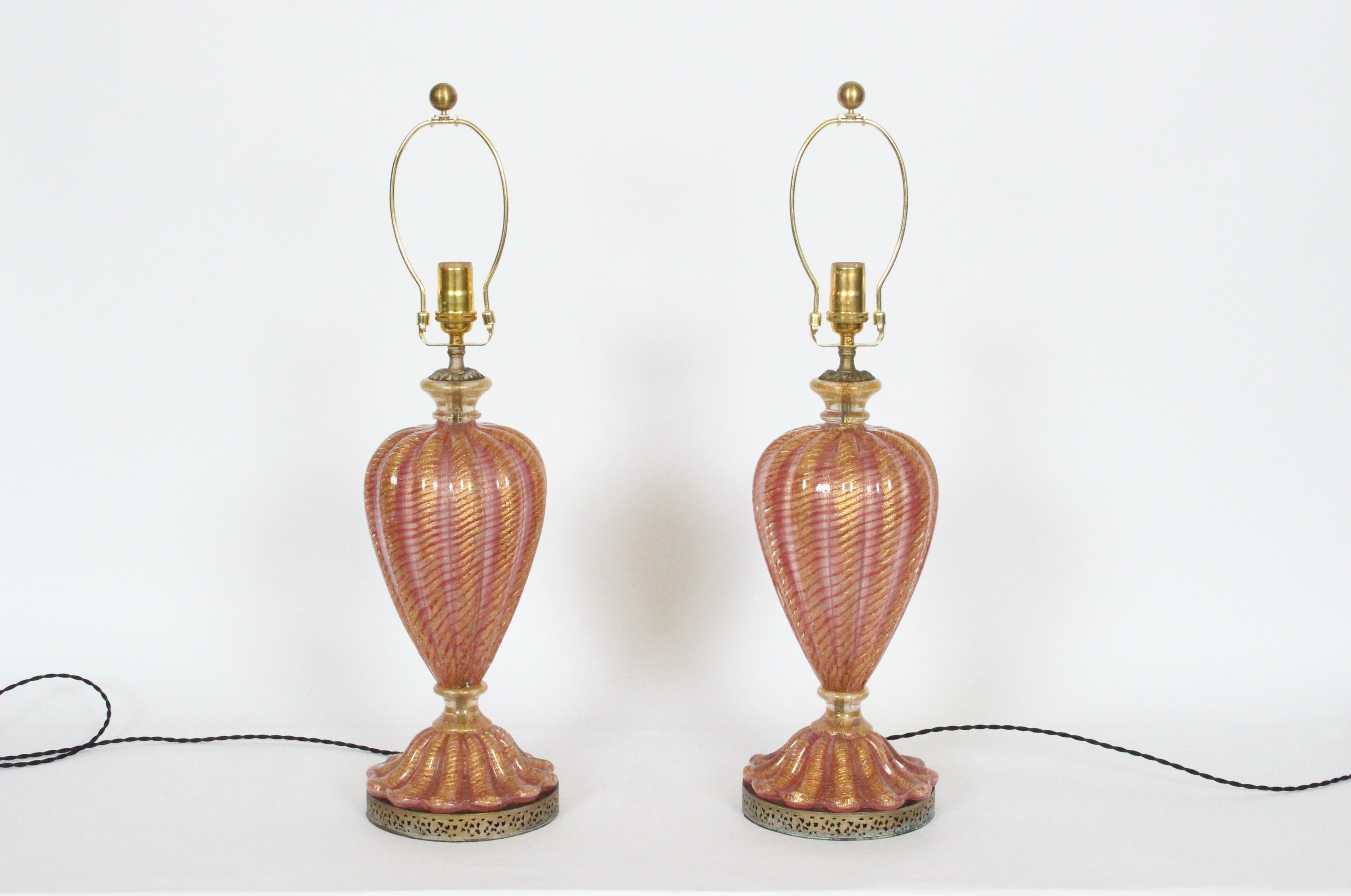 Pair of Barovier & Toso Rose Pink Murano Glass with Gold inclusions, circa 1950. Featuring translucent hand blown Rose Pink (6.5D) glass forms, spiraling gold highlights, lower scalloped fluting atop round pierced, patinated Brass (7D) bases. 20H to